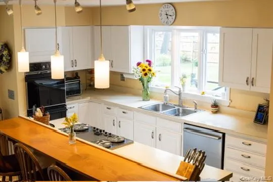 Updated white cabinetry, light-toned countertops, double wall ovens, a cooktop, and a double basin sink Updated white cabinetry, light-toned countertops, double wall ovens, a cooktop, and a double basin sink