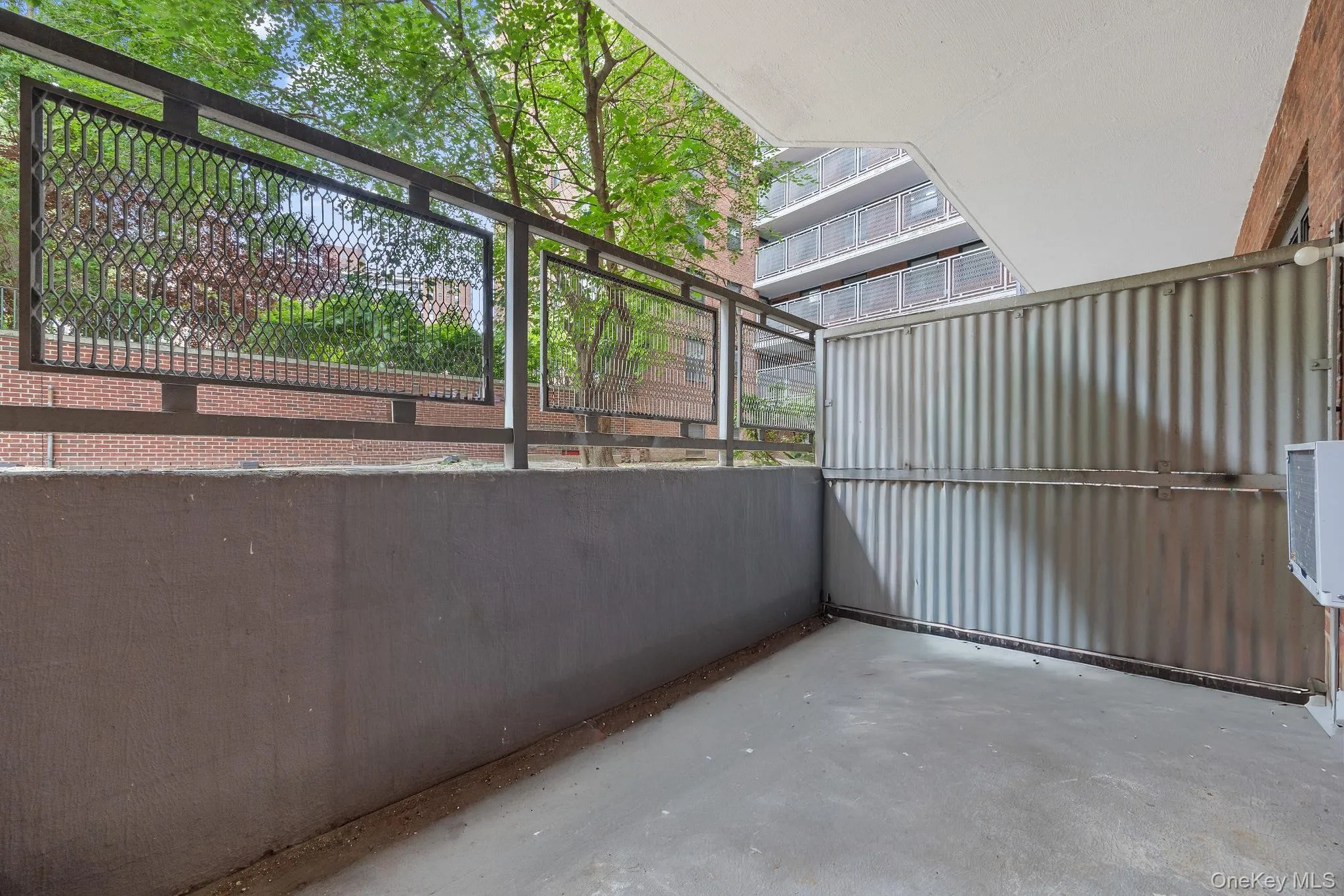 Private outdoor balcony featuring a concrete floor and a decorative metal railing Private outdoor balcony featuring a concrete floor and a decorative metal railing