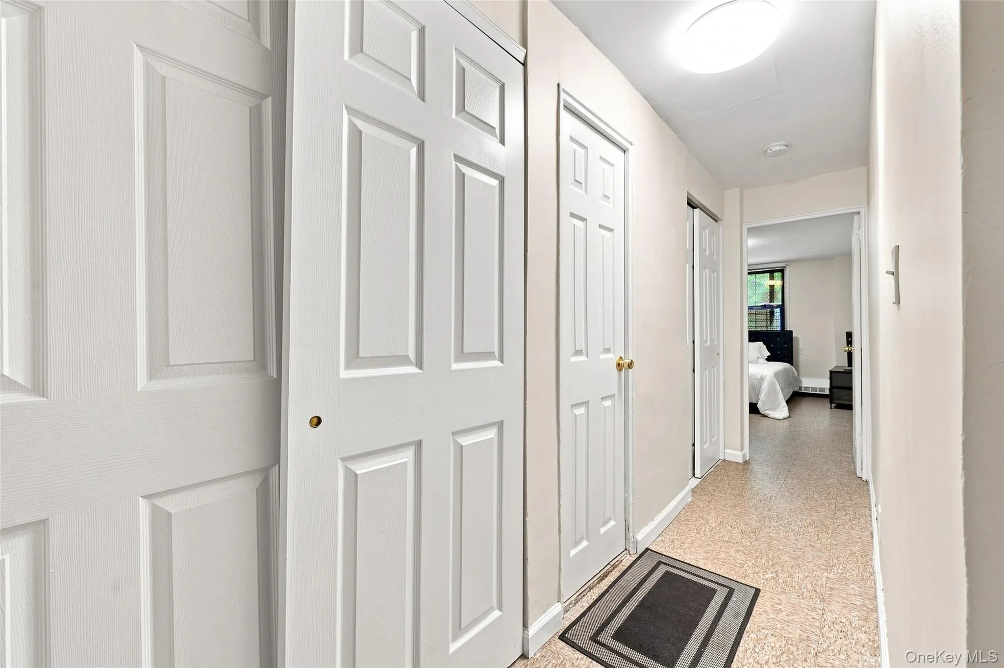 Hallway with panel doors, flush mount lighting, and light-toned flooring Hallway with panel doors, flush mount lighting, and light-toned flooring