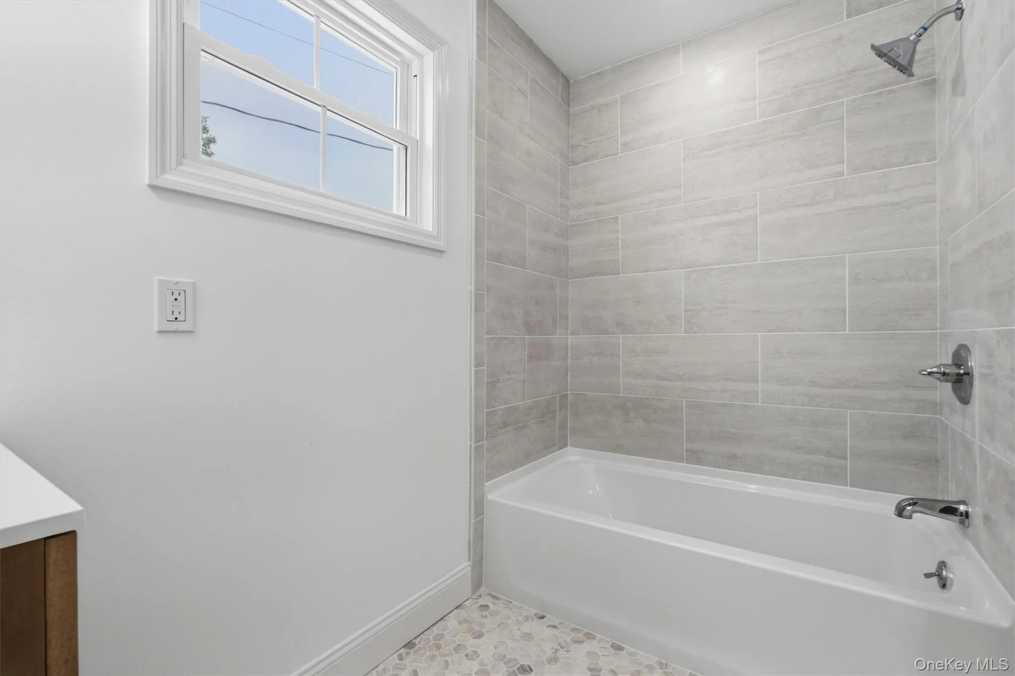 Full-size bathtub with subway tile surround, chrome fixtures, and a pebble-style floor Full-size bathtub with subway tile surround, chrome fixtures, and a pebble-style floor