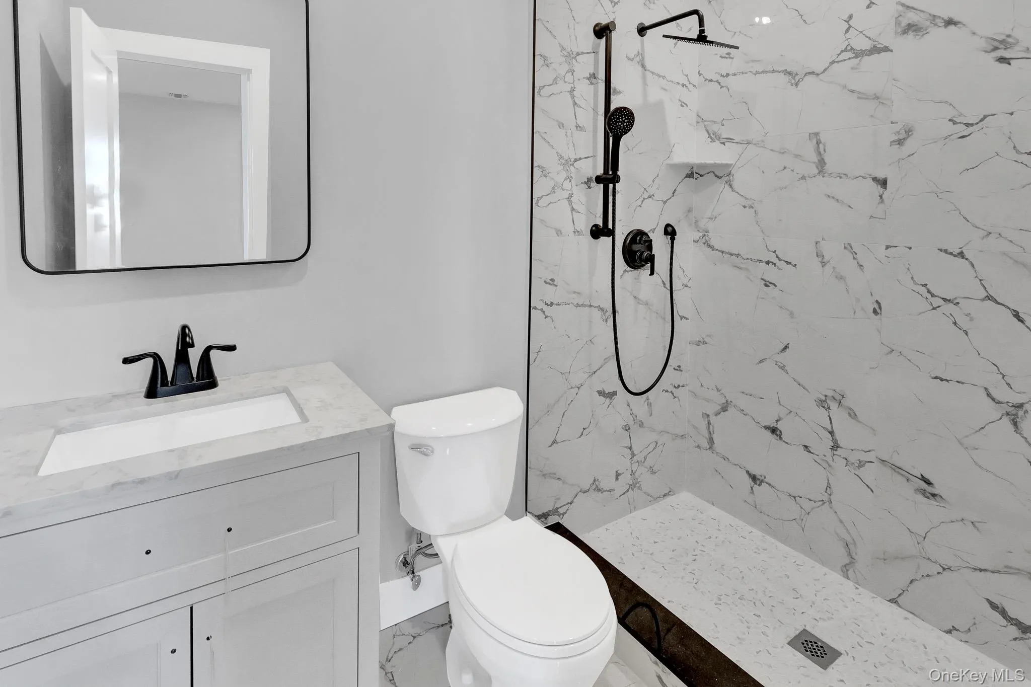 White vanity with a light gray countertop and black faucet White vanity with a light gray countertop and black faucet