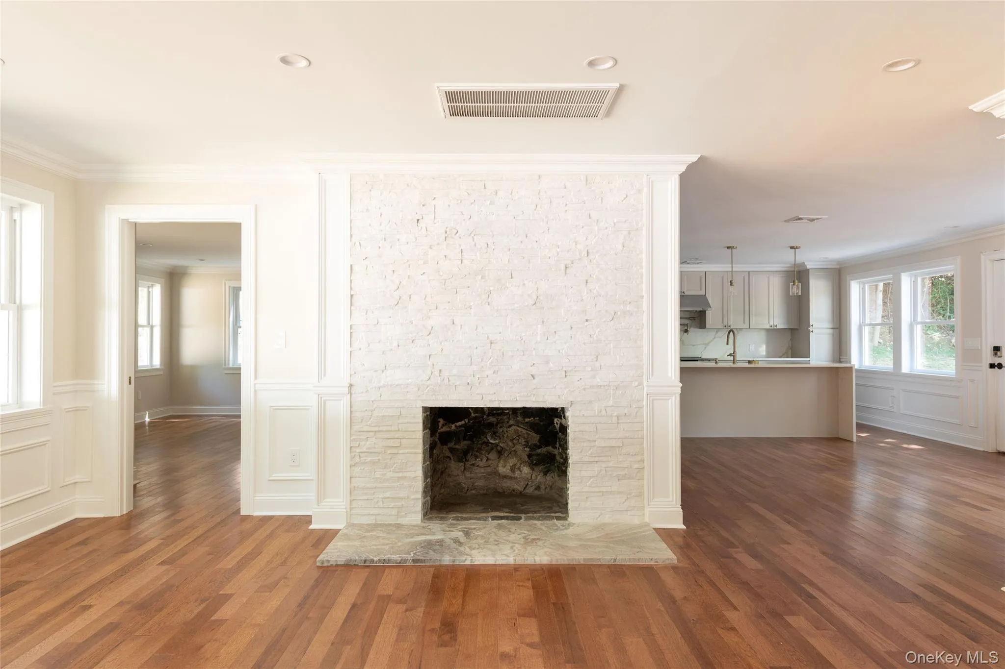 Living room and fireplace with access to primary bedroom on left and kitchen/dining on right. Living room and fireplace with access to primary bedroom on left and kitchen/dining on right.