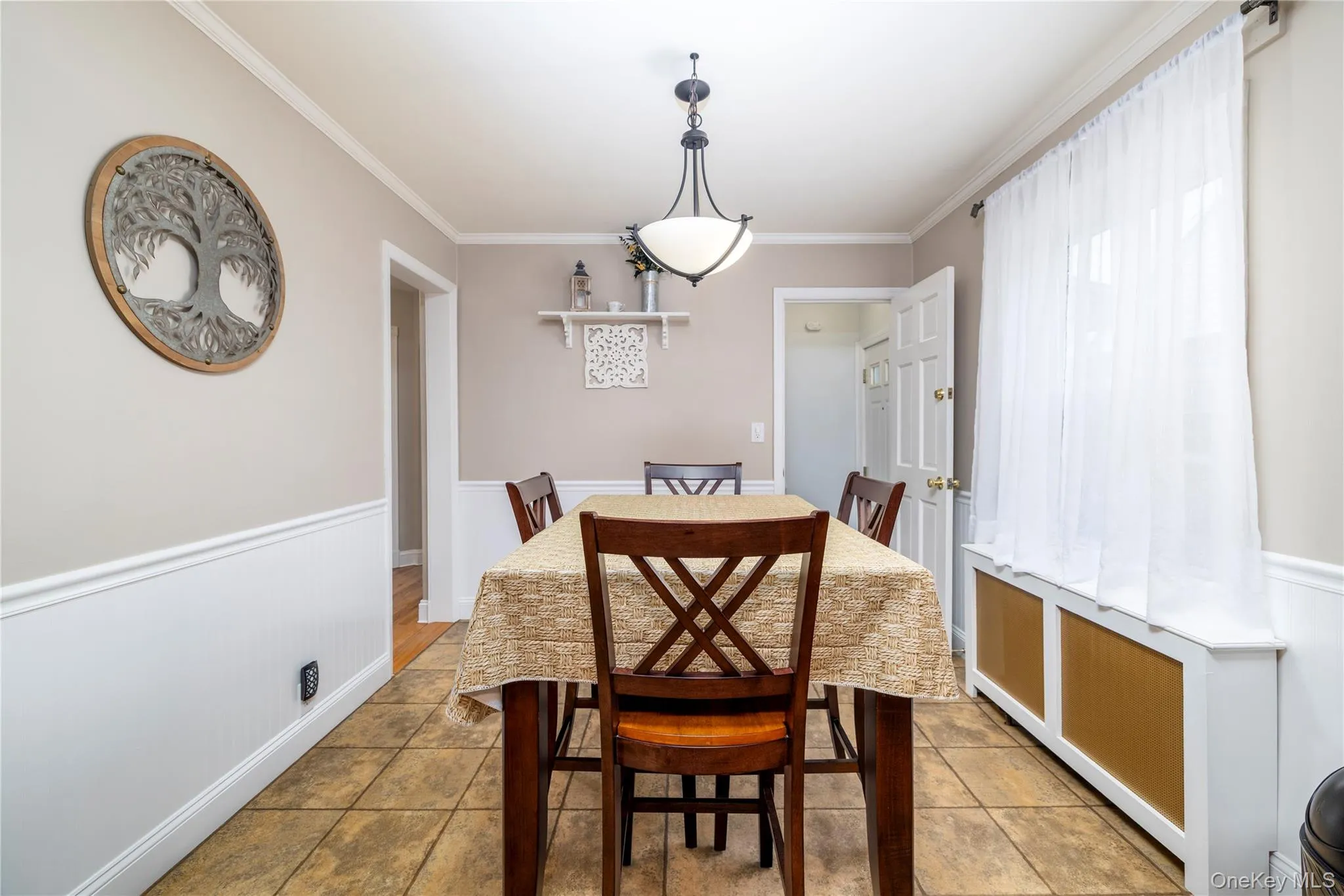 Dining space featuring wainscoting, ornamental molding, and light tile patterned floors Dining space featuring wainscoting, ornamental molding, and light tile patterned floors