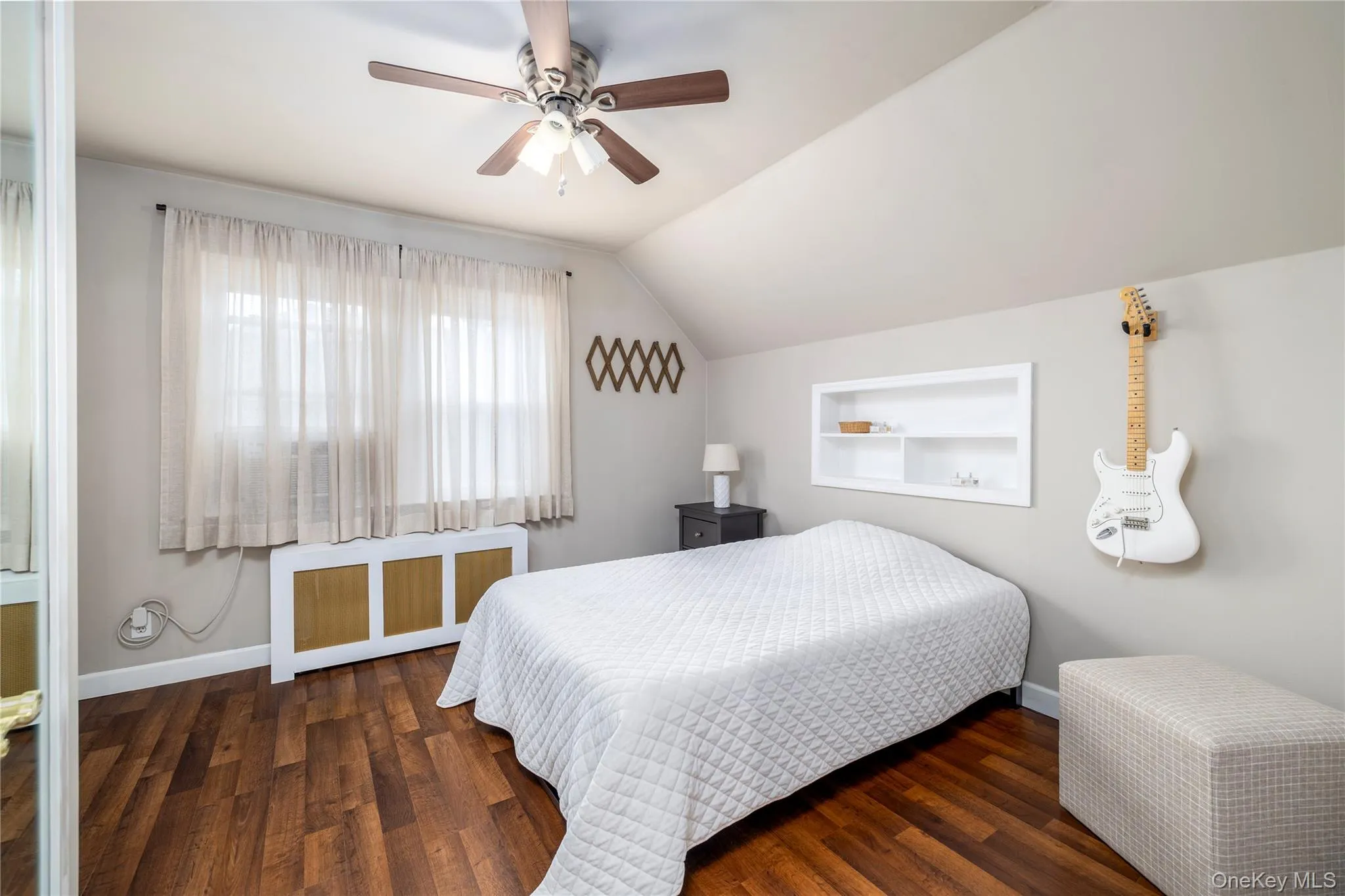 Bedroom with baseboards, wood finished floors, a ceiling fan, radiator, and vaulted ceiling Bedroom with baseboards, wood finished floors, a ceiling fan, radiator, and vaulted ceiling