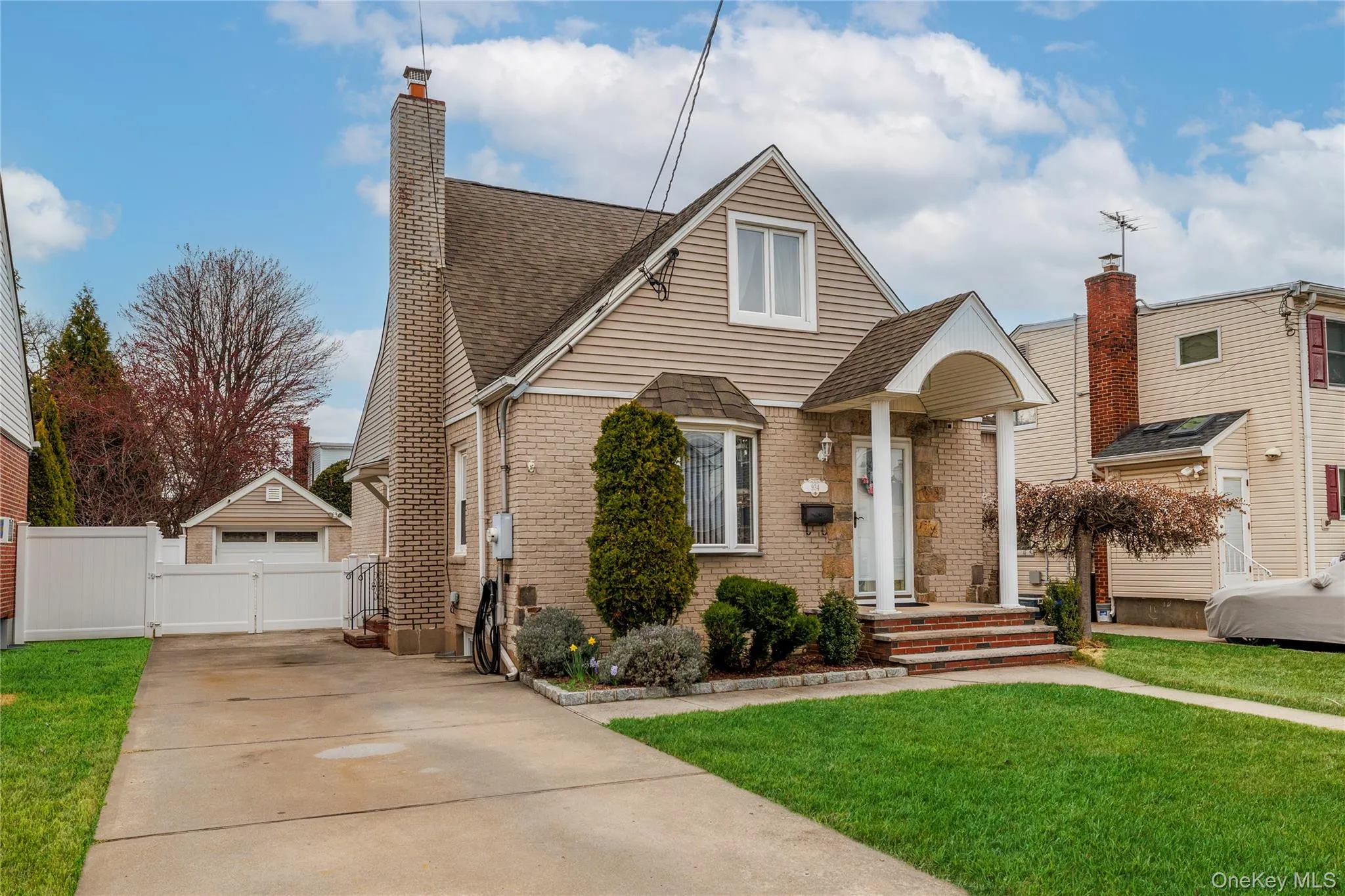 View of front facade with a front yard, a gate, roof with shingles, a chimney, and brick siding View of front facade with a front yard, a gate, roof with shingles, a chimney, and brick siding