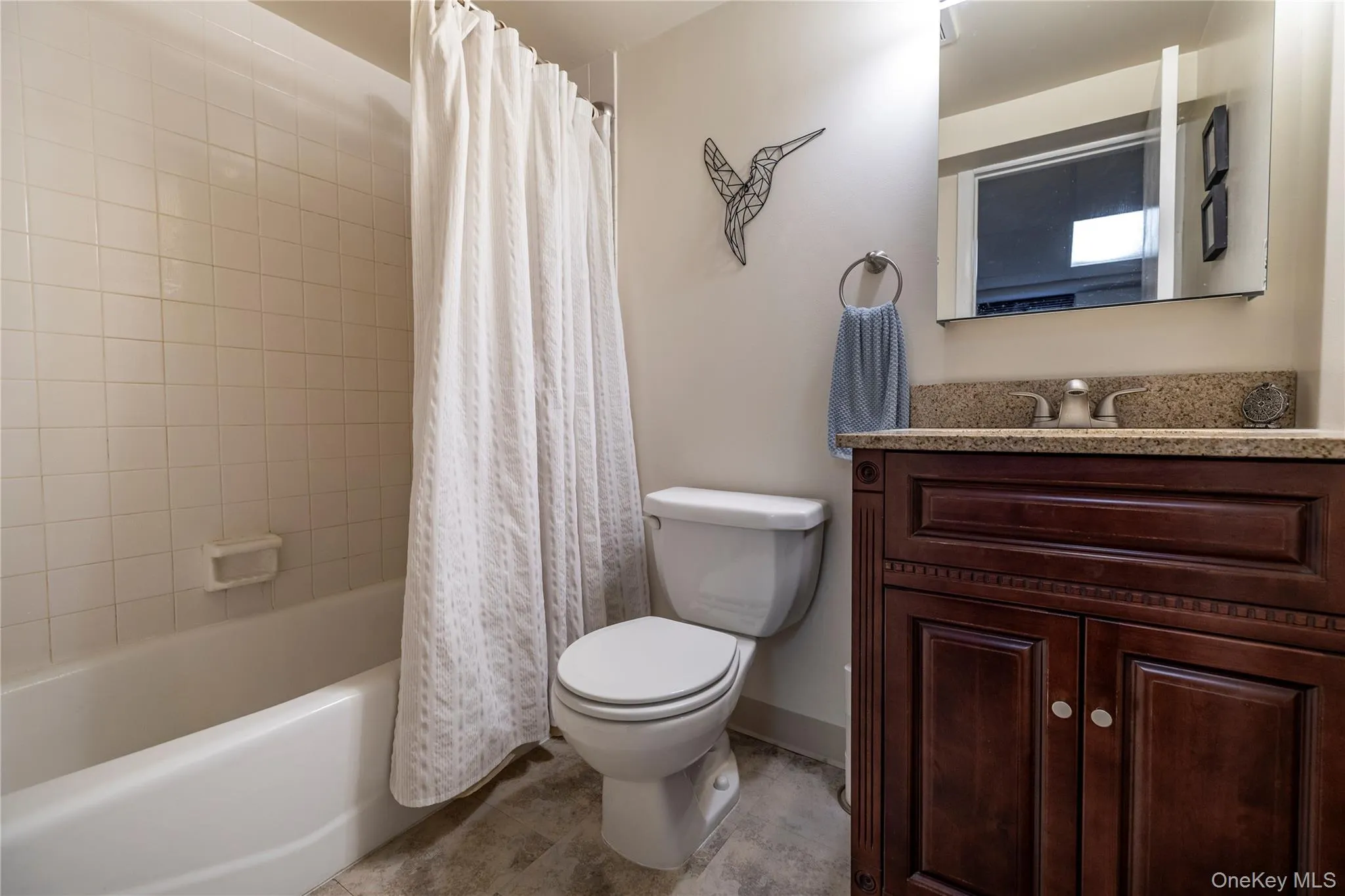 Bathroom featuring baseboards, toilet, tile patterned floors, vanity, and shower / bathtub combination with curtain Bathroom featuring baseboards, toilet, tile patterned floors, vanity, and shower / bathtub combination with curtain