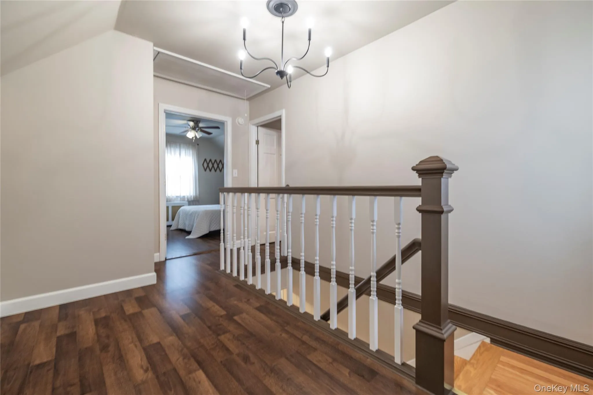 Hall with an upstairs landing, lofted ceiling, an inviting chandelier, baseboards, and wood finished floors Hall with an upstairs landing, lofted ceiling, an inviting chandelier, baseboards, and wood finished floors