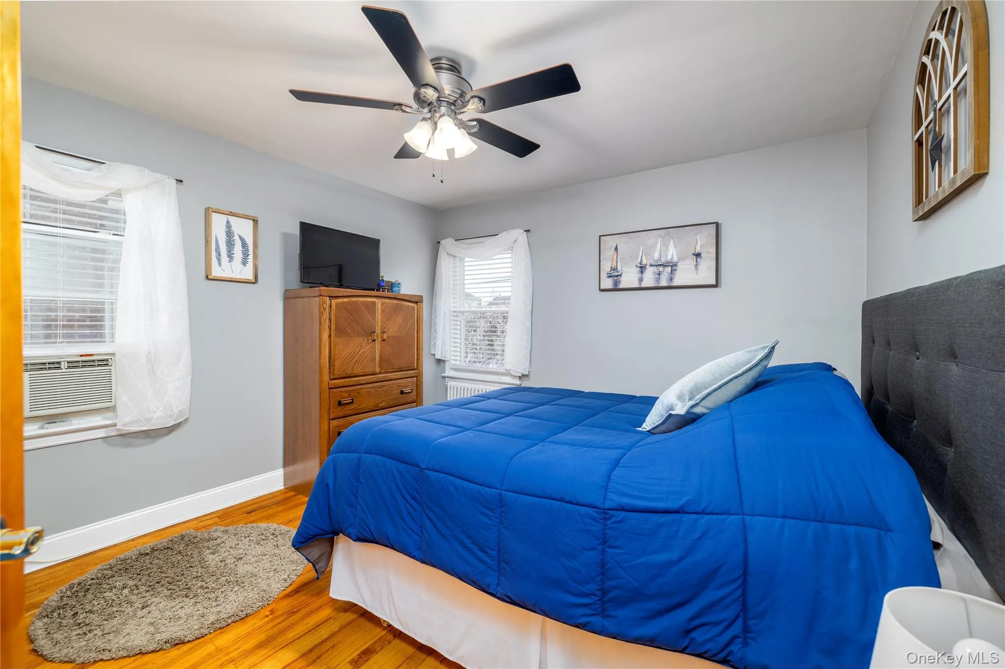 Bedroom featuring cooling unit, baseboards, ceiling fan, and wood finished floors Bedroom featuring cooling unit, baseboards, ceiling fan, and wood finished floors