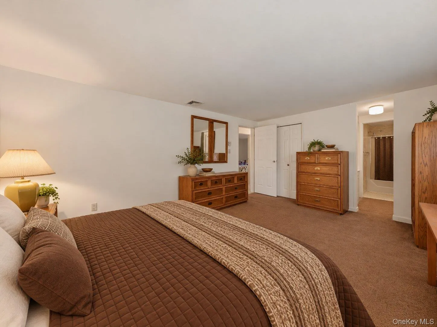 Virtually staged primary bedroom highlighting the generous room size, storage, and convenient connection to the adjoining bathroom. Virtually staged primary bedroom highlighting the generous room size, storage, and convenient connection to the adjoining bathroom.