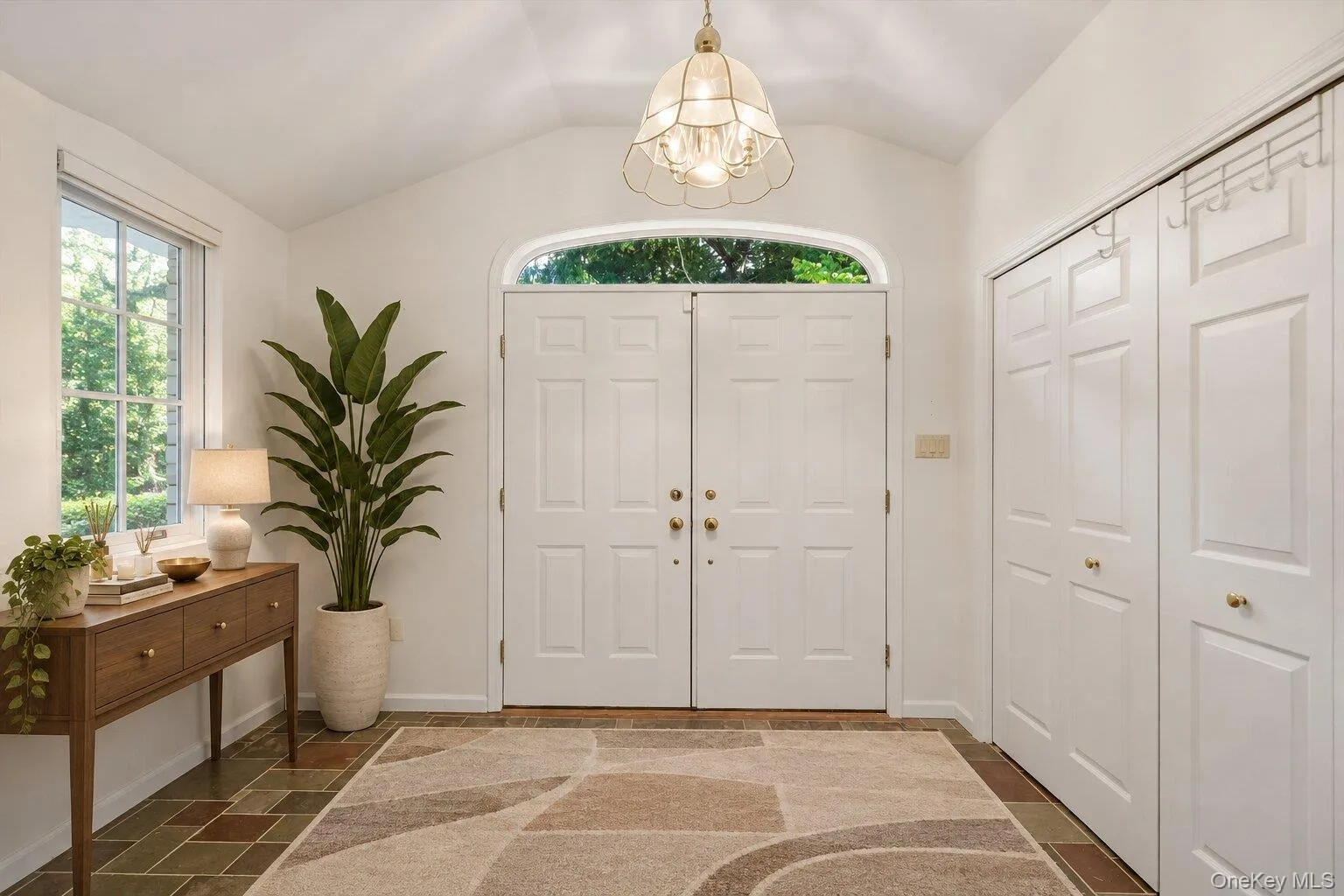 Spacious entry foyer featuring double doors, natural light, a vaulted ceiling, and convenient storage closets. Spacious entry foyer featuring double doors, natural light, a vaulted ceiling, and convenient storage closets.