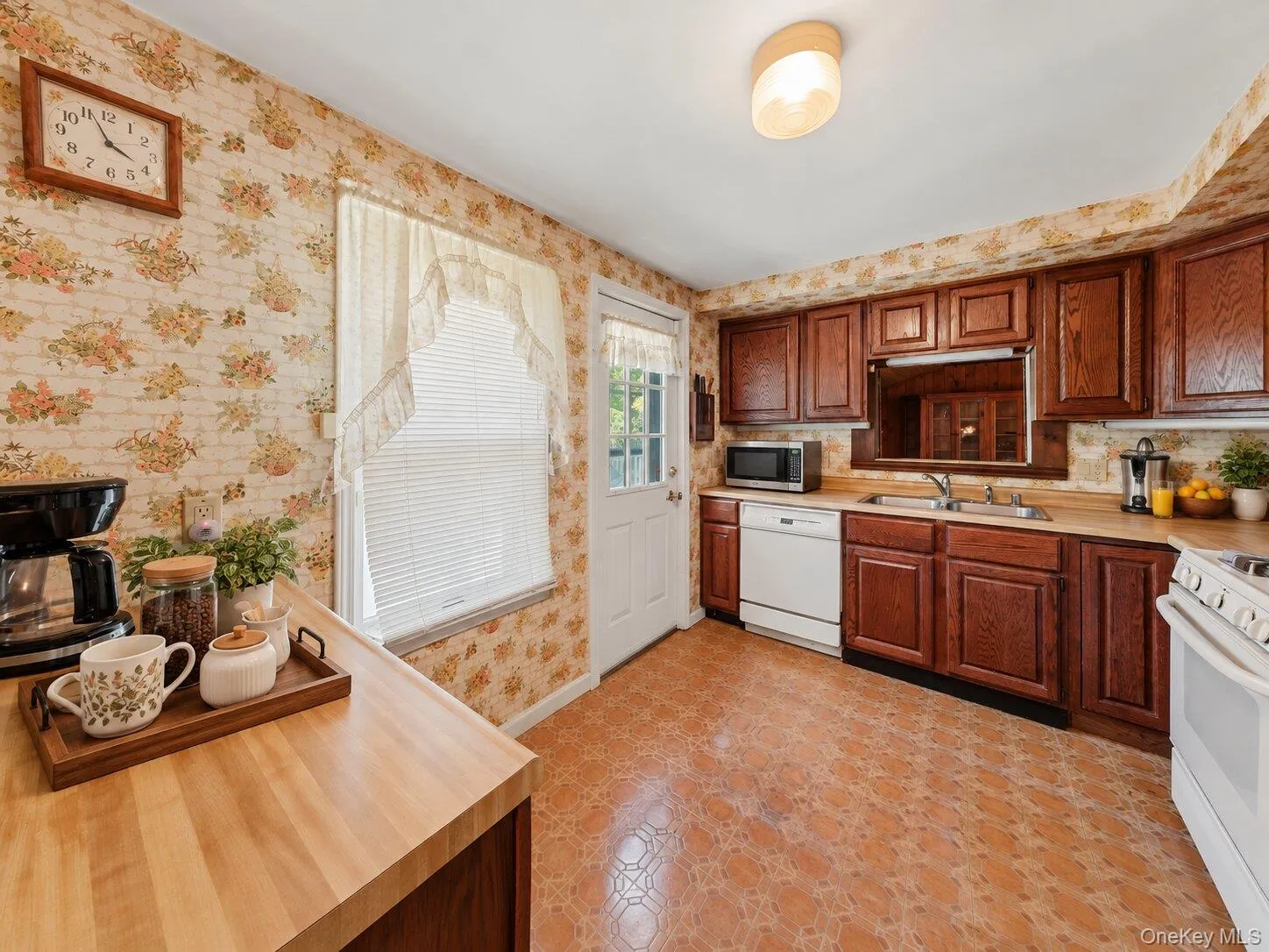 Virtually decluttered kitchen showcasing the generous counter space, cabinetry, and convenient exterior access Virtually decluttered kitchen showcasing the generous counter space, cabinetry, and convenient exterior access