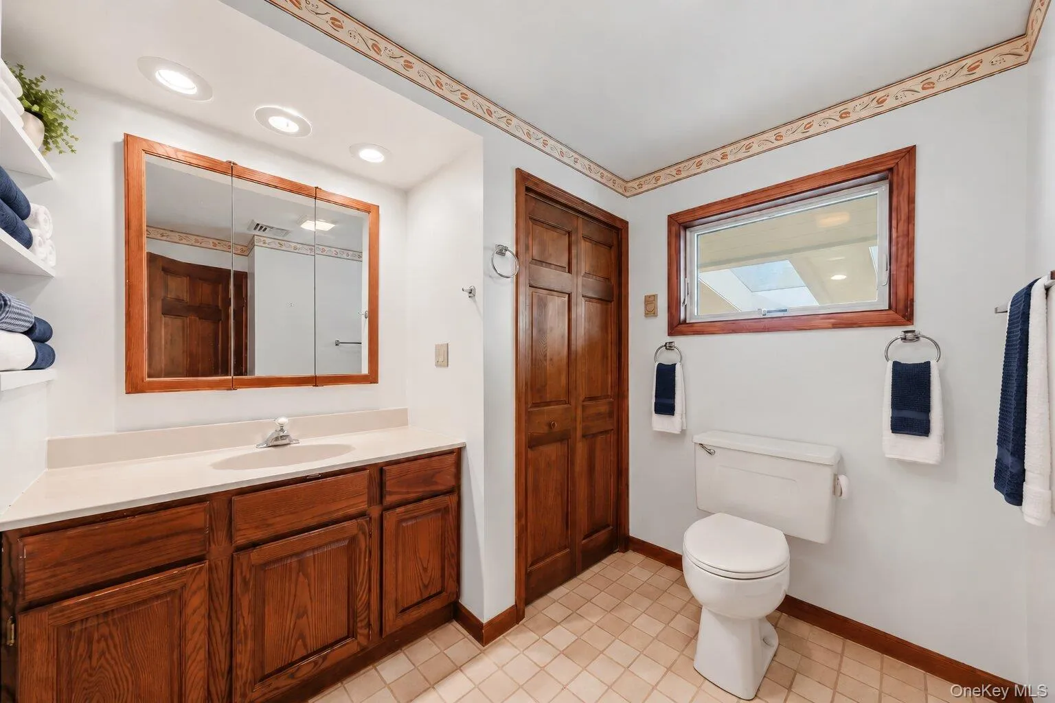 Additional bathroom view showcasing the spacious vanity, wood cabinetry, natural light, and convenient storage. Additional bathroom view showcasing the spacious vanity, wood cabinetry, natural light, and convenient storage.