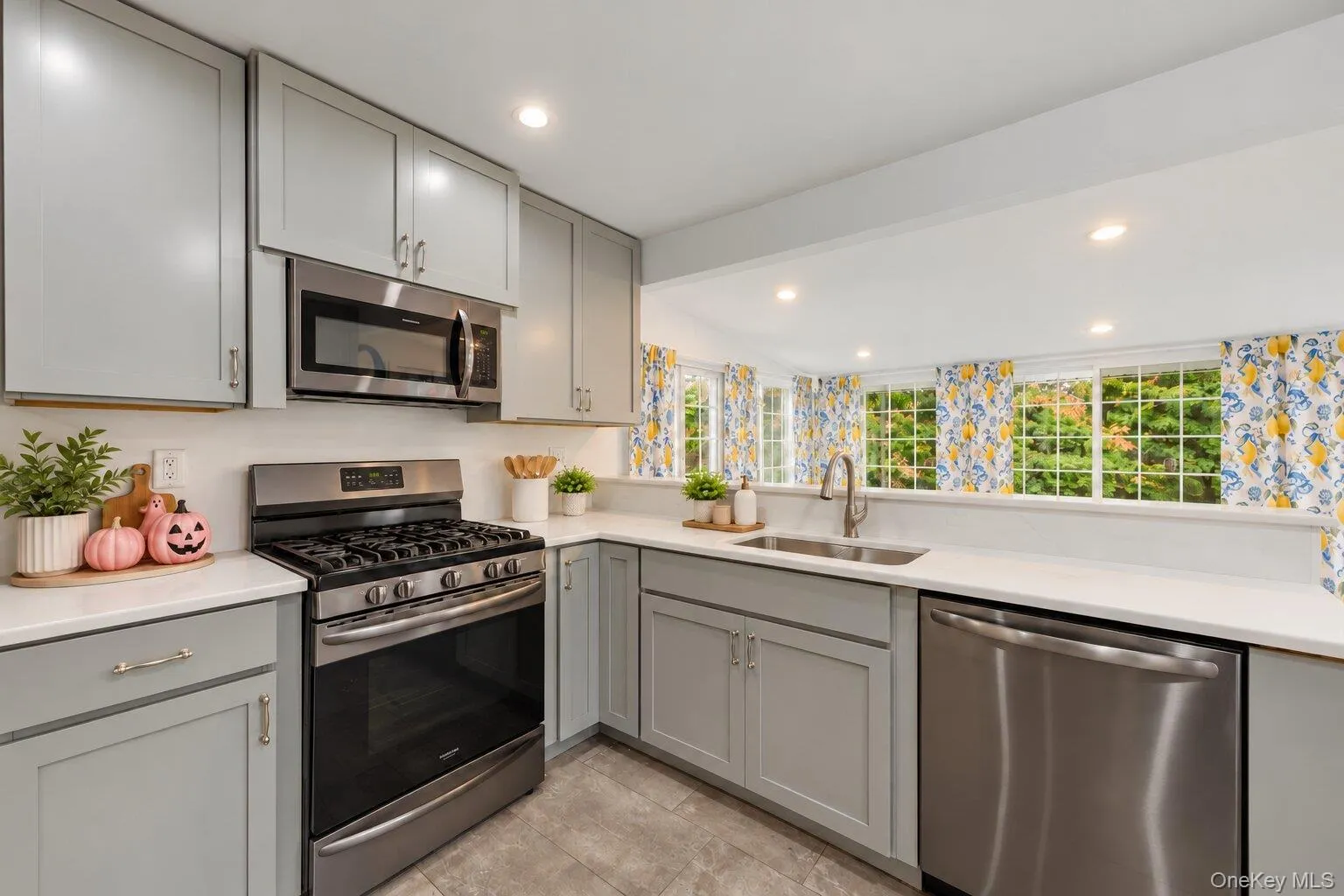 Virtually decluttered. Kitchen featuring a stainless steel gas range, built-in microwave, dishwasher, gray cabinets, and white countertops. Virtually decluttered. Kitchen featuring a stainless steel gas range, built-in microwave, dishwasher, gray cabinets, and white countertops.