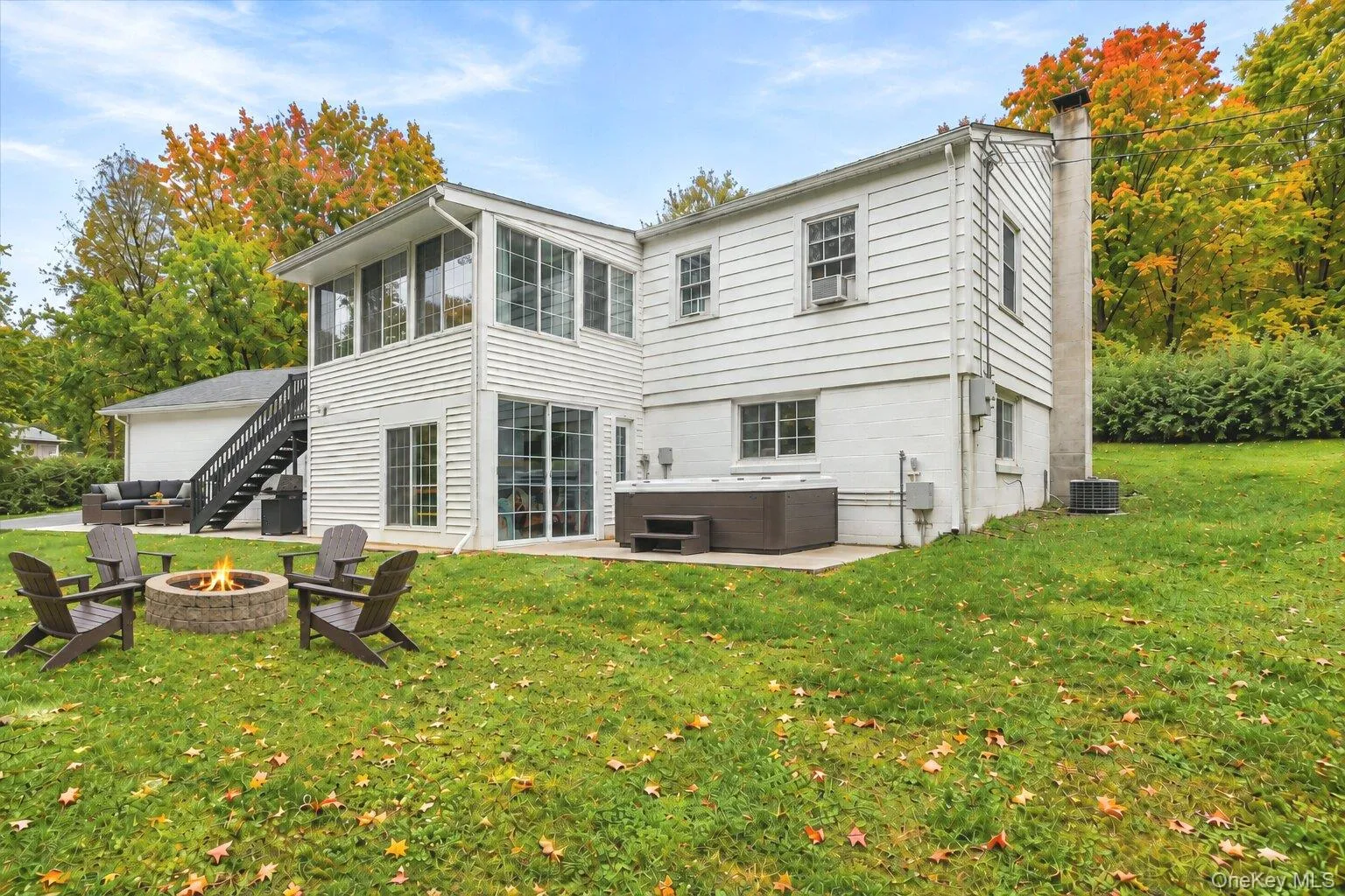 Virtually staged furniture. Rear exterior view featuring white siding, a grassy yard, and a patio seating area with two chairs and a small table. Virtually staged furniture. Rear exterior view featuring white siding, a grassy yard, and a patio seating area with two chairs and a small table.