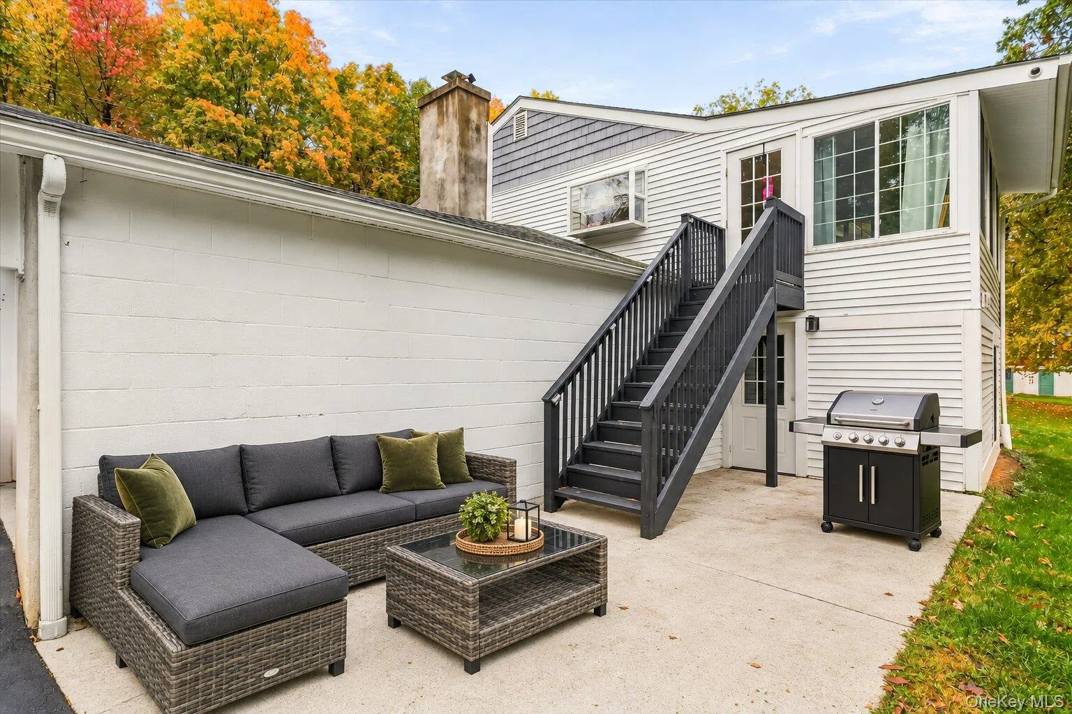 Virtually staged Mattress, throw Pillow, barbeque Grill and decluttered. Outdoor concrete patio featuring a gray rattan sectional sofa, matching coffee table, barbecue grill, and exterior staircase leading to the upper level. Virtually staged Mattress, throw Pillow, barbeque Grill and decluttered. Outdoor concrete patio featuring a gray rattan sectional sofa, matching coffee table, barbecue grill, and exterior staircase leading to the upper level.