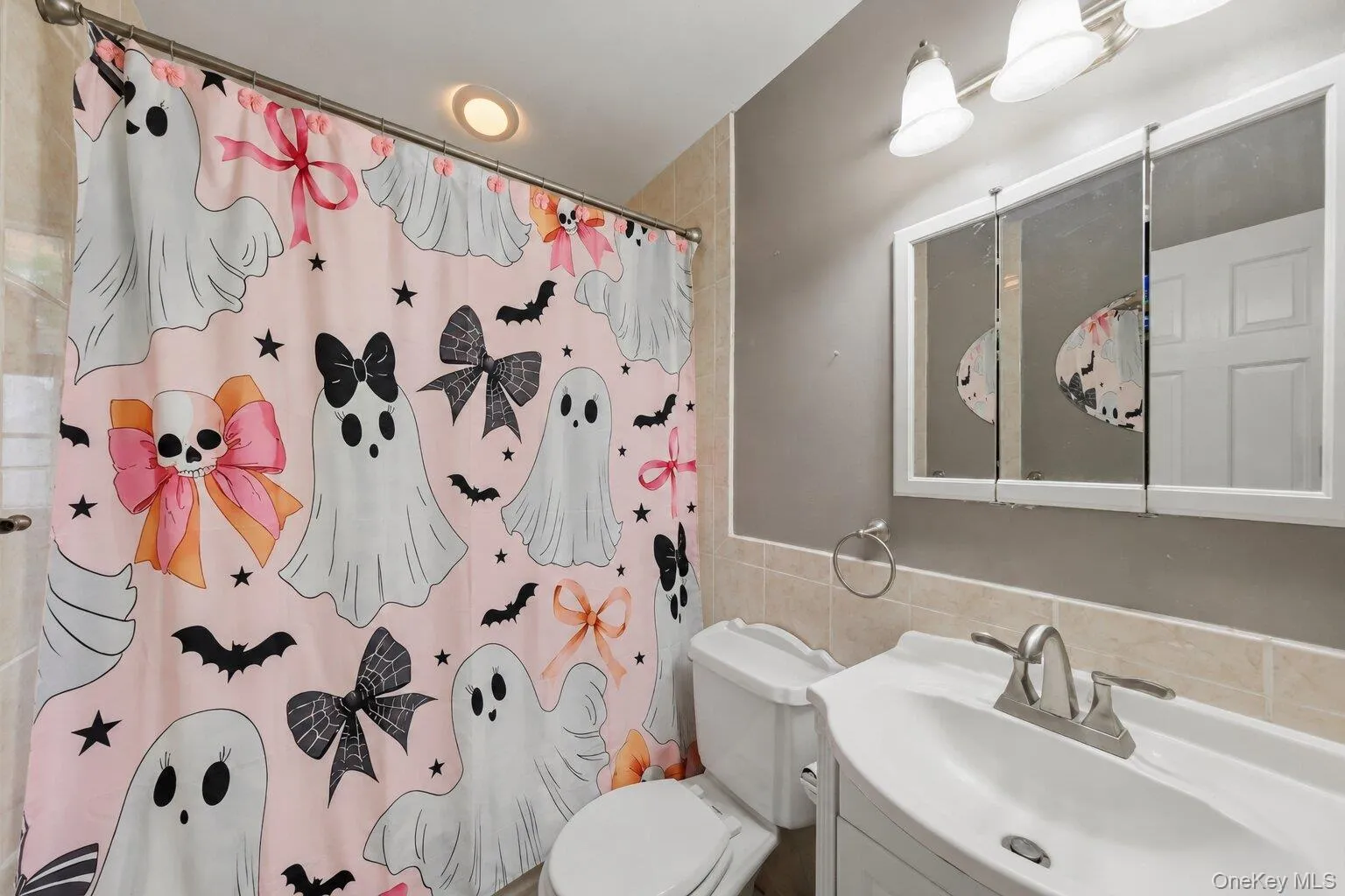 Full bathroom featuring a tub and shower combination, white vanity with storage, mirrored medicine cabinet, and tiled wall accents. Full bathroom featuring a tub and shower combination, white vanity with storage, mirrored medicine cabinet, and tiled wall accents.