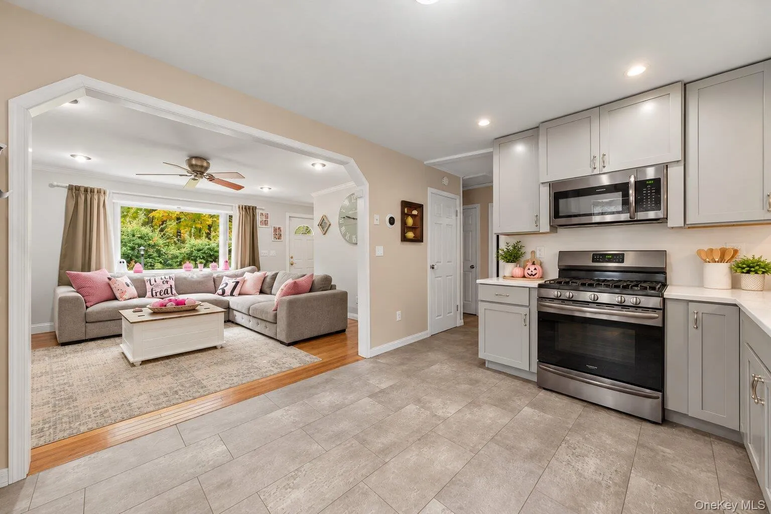 Virtually decluttered. Kitchen with stainless steel gas range, built-in microwave, gray cabinetry, and an arched opening leading to the living room. Virtually decluttered. Kitchen with stainless steel gas range, built-in microwave, gray cabinetry, and an arched opening leading to the living room.