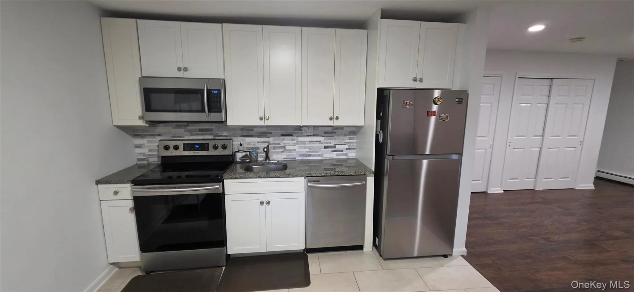 White cabinetry, stainless steel appliances, mosaic tile backsplash, and stone-finish countertops White cabinetry, stainless steel appliances, mosaic tile backsplash, and stone-finish countertops