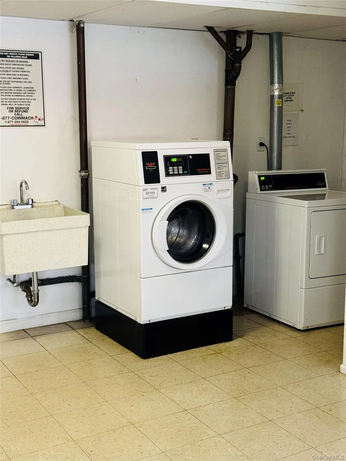 Laundry facility featuring a front-load washer, top-load dryer, utility sink, and tiled flooring Laundry facility featuring a front-load washer, top-load dryer, utility sink, and tiled flooring