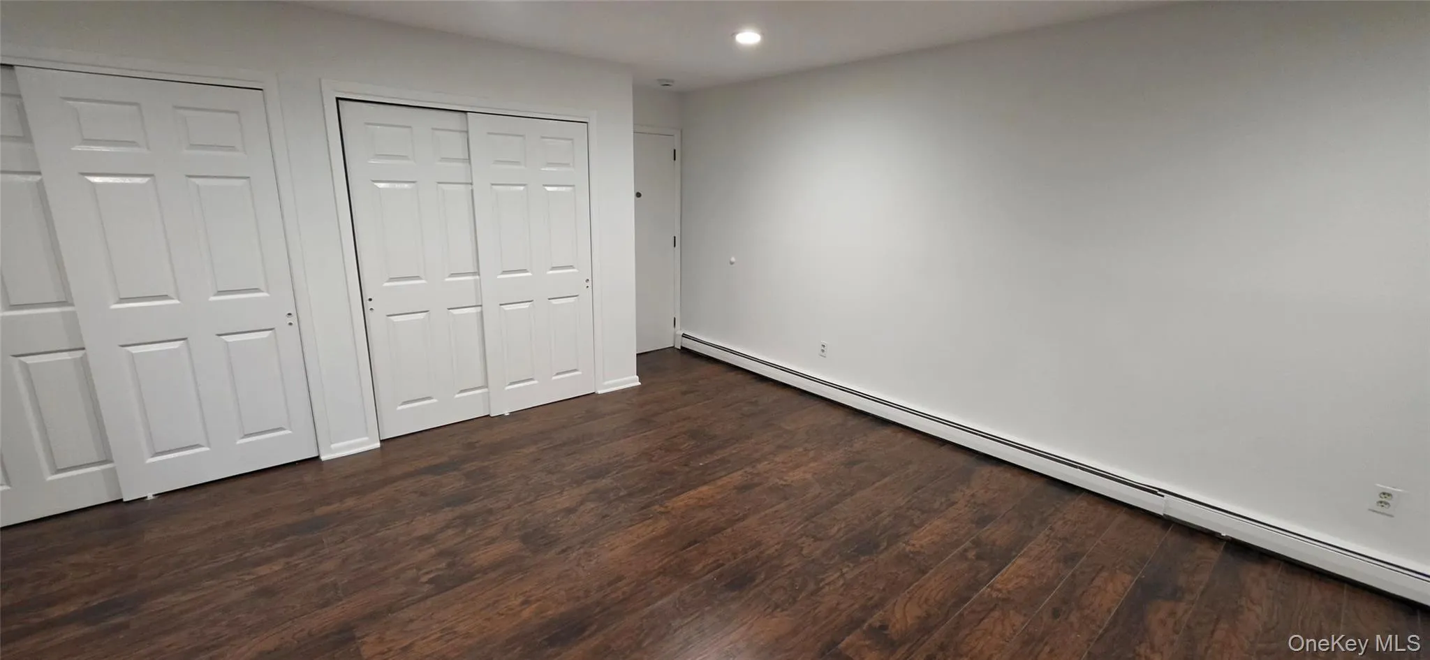 Wood-finish flooring with white walls and recessed lighting Wood-finish flooring with white walls and recessed lighting