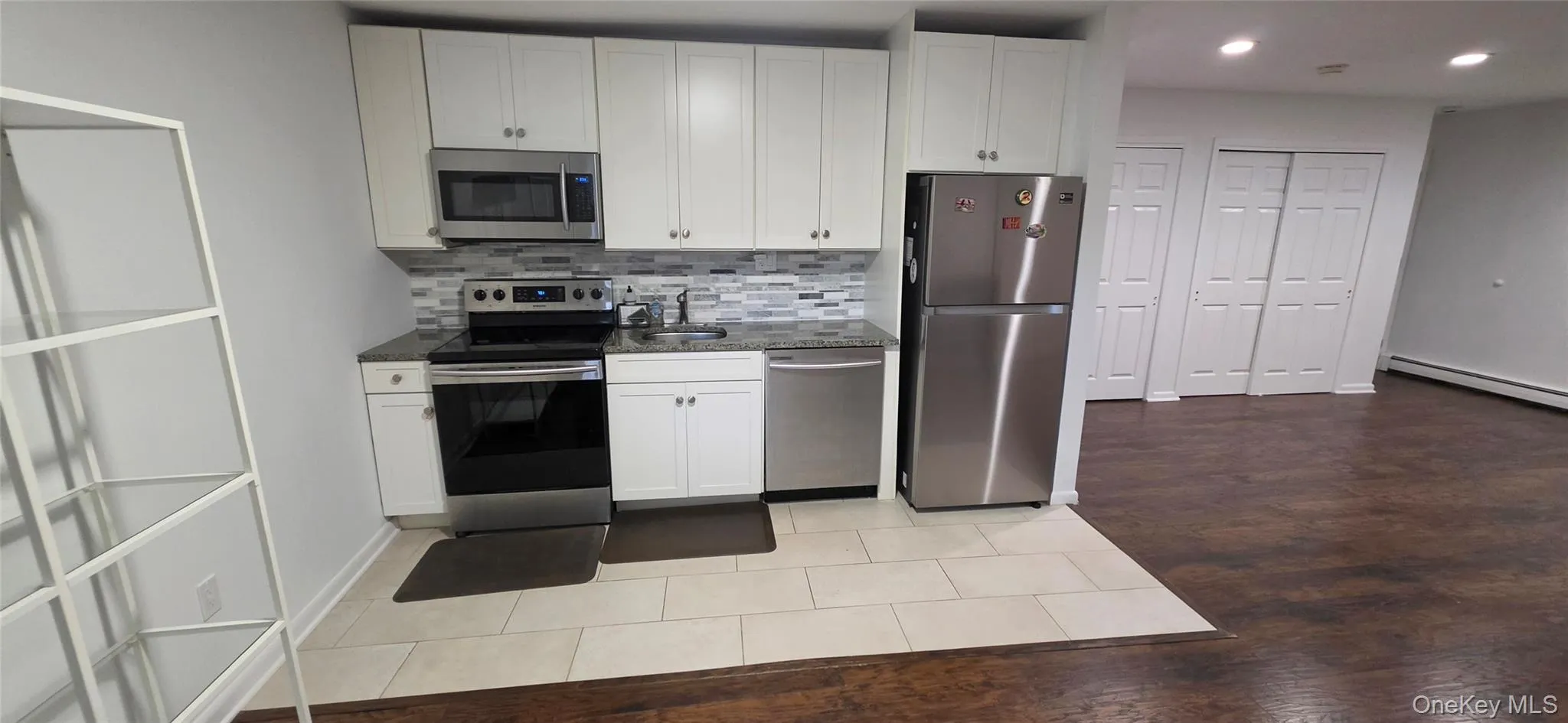 White cabinetry with stainless steel appliances, mosaic tile backsplash, and granite-finish countertops White cabinetry with stainless steel appliances, mosaic tile backsplash, and granite-finish countertops