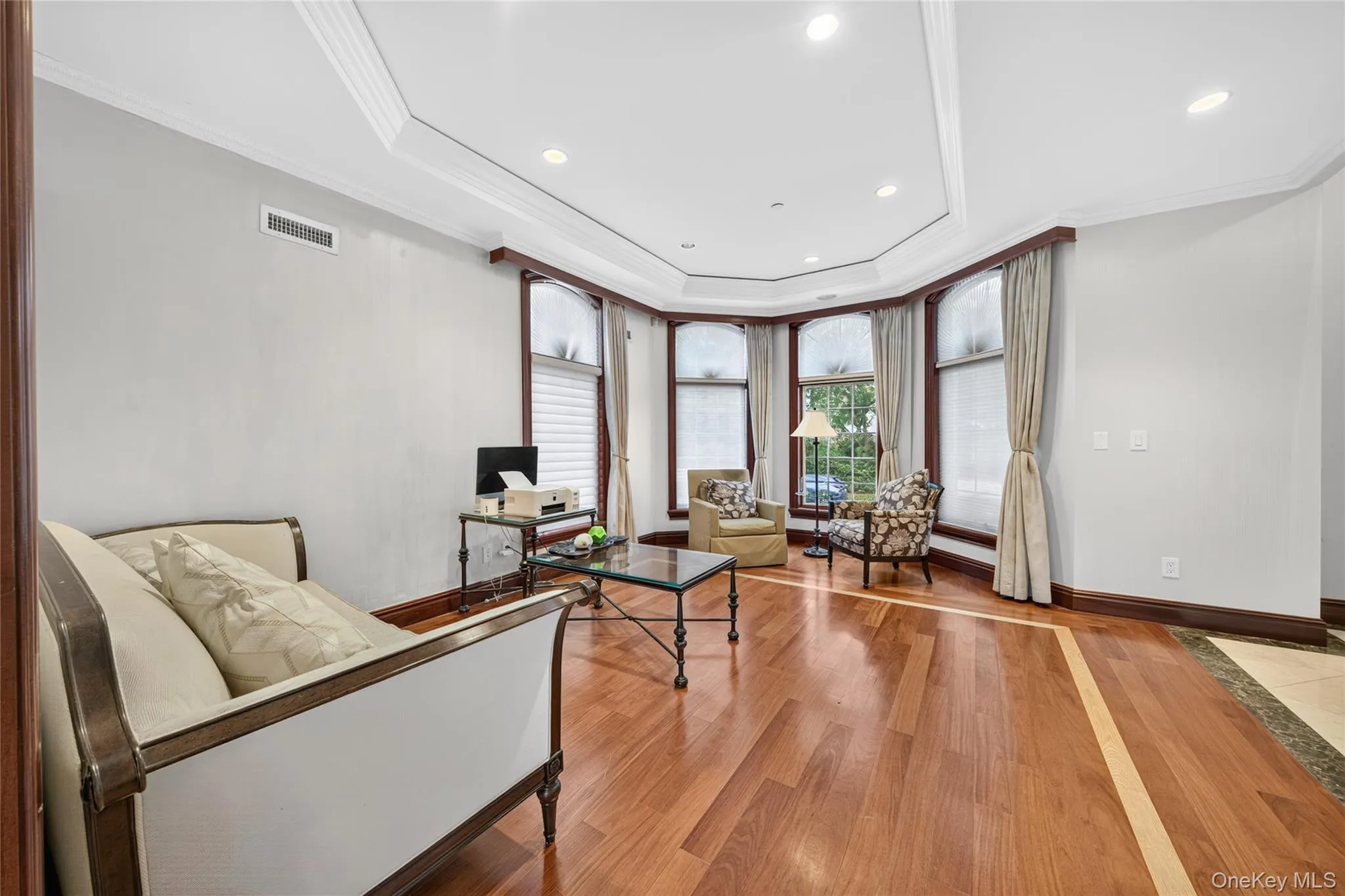 Recessed lighting, crown molding, tray ceiling, hardwood flooring with inlaid detailing, and large bay windows Recessed lighting, crown molding, tray ceiling, hardwood flooring with inlaid detailing, and large bay windows