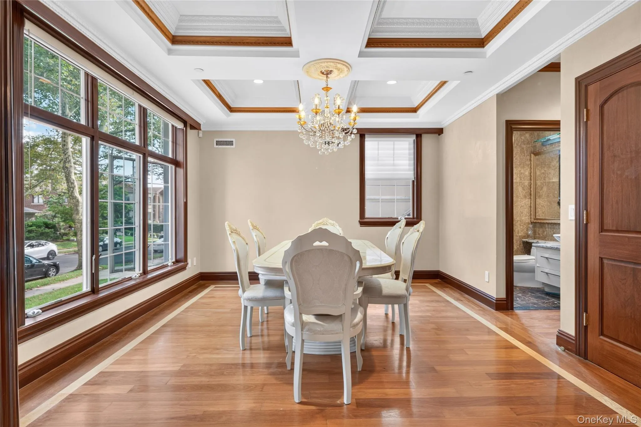 Hardwood flooring with inlay, extensive wood trim, multiple large windows, coffered ceiling, and a crystal chandelier Hardwood flooring with inlay, extensive wood trim, multiple large windows, coffered ceiling, and a crystal chandelier