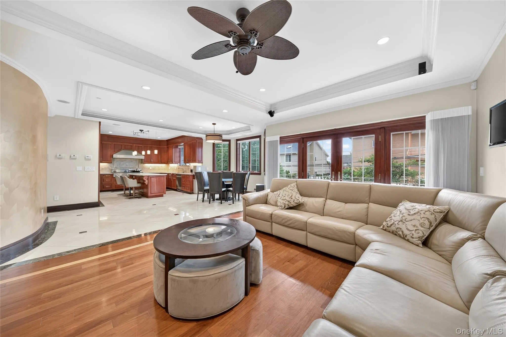 Open-concept living area featuring wood-finish flooring, a tray ceiling with recessed lighting, and a ceiling fan Open-concept living area featuring wood-finish flooring, a tray ceiling with recessed lighting, and a ceiling fan
