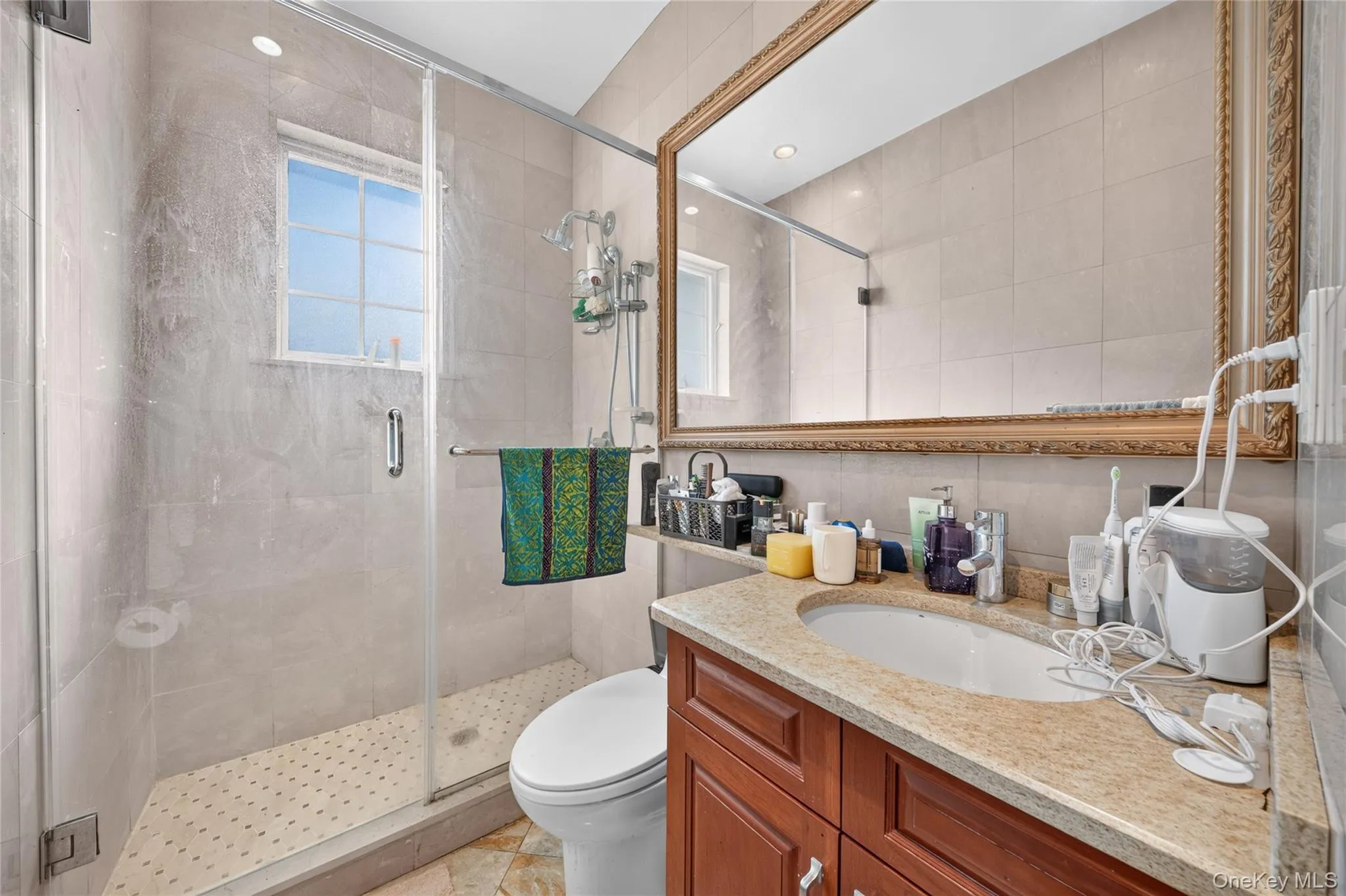Framed wall mirror, single vanity with wood-finish cabinetry, granite countertop, and integrated sink Framed wall mirror, single vanity with wood-finish cabinetry, granite countertop, and integrated sink