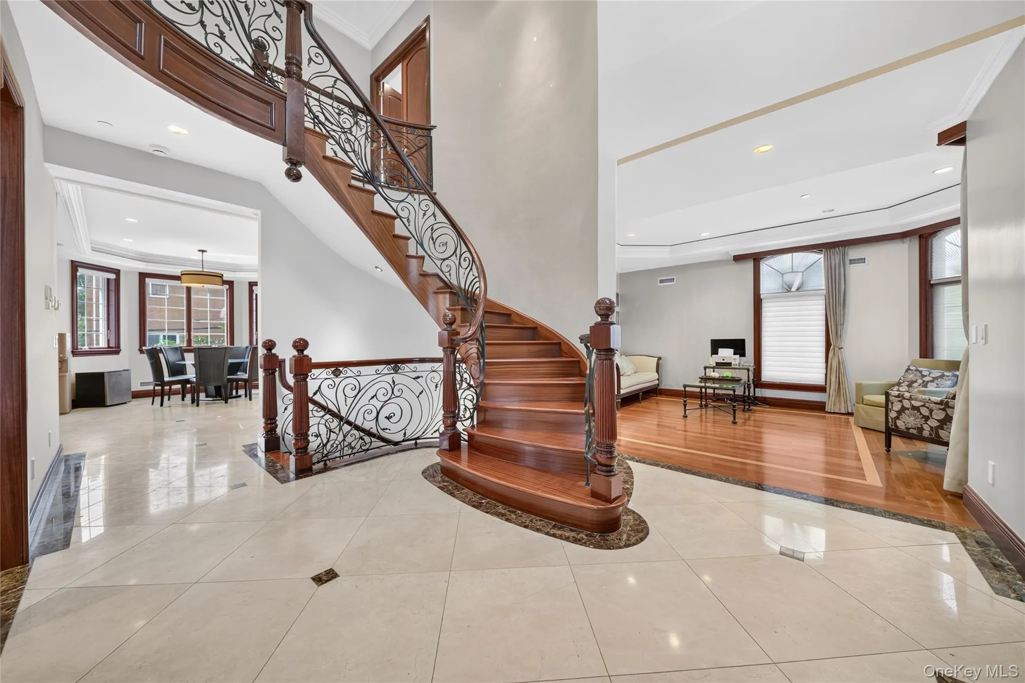 Grand entry featuring a curved staircase with ornate wrought iron balusters and wood banister Grand entry featuring a curved staircase with ornate wrought iron balusters and wood banister