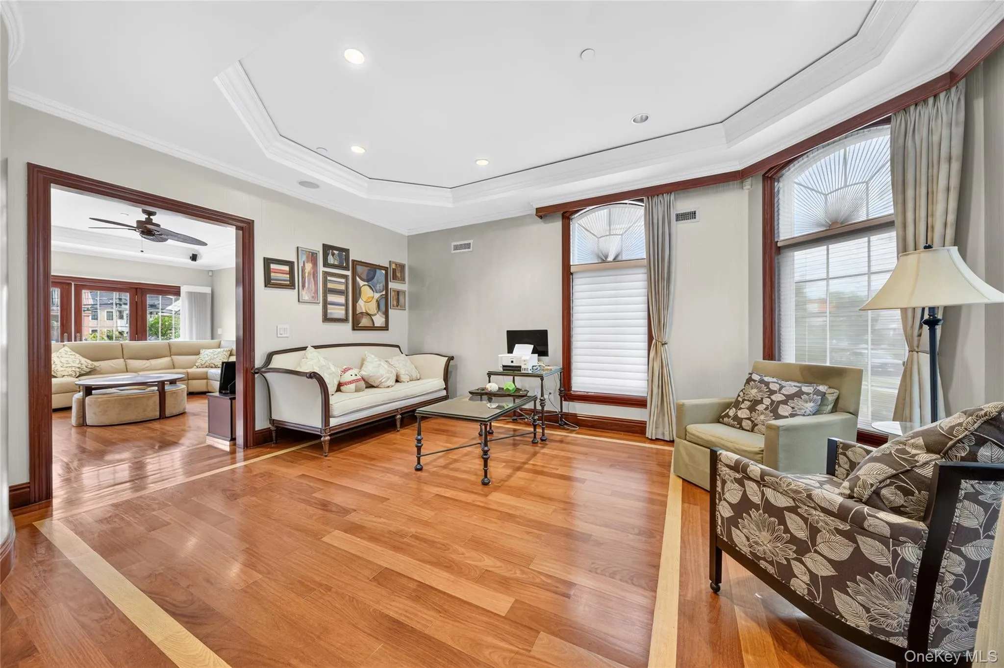 Hardwood flooring with a decorative inlay, tray ceiling with recessed lighting, and arched windows with detailed muntins Hardwood flooring with a decorative inlay, tray ceiling with recessed lighting, and arched windows with detailed muntins