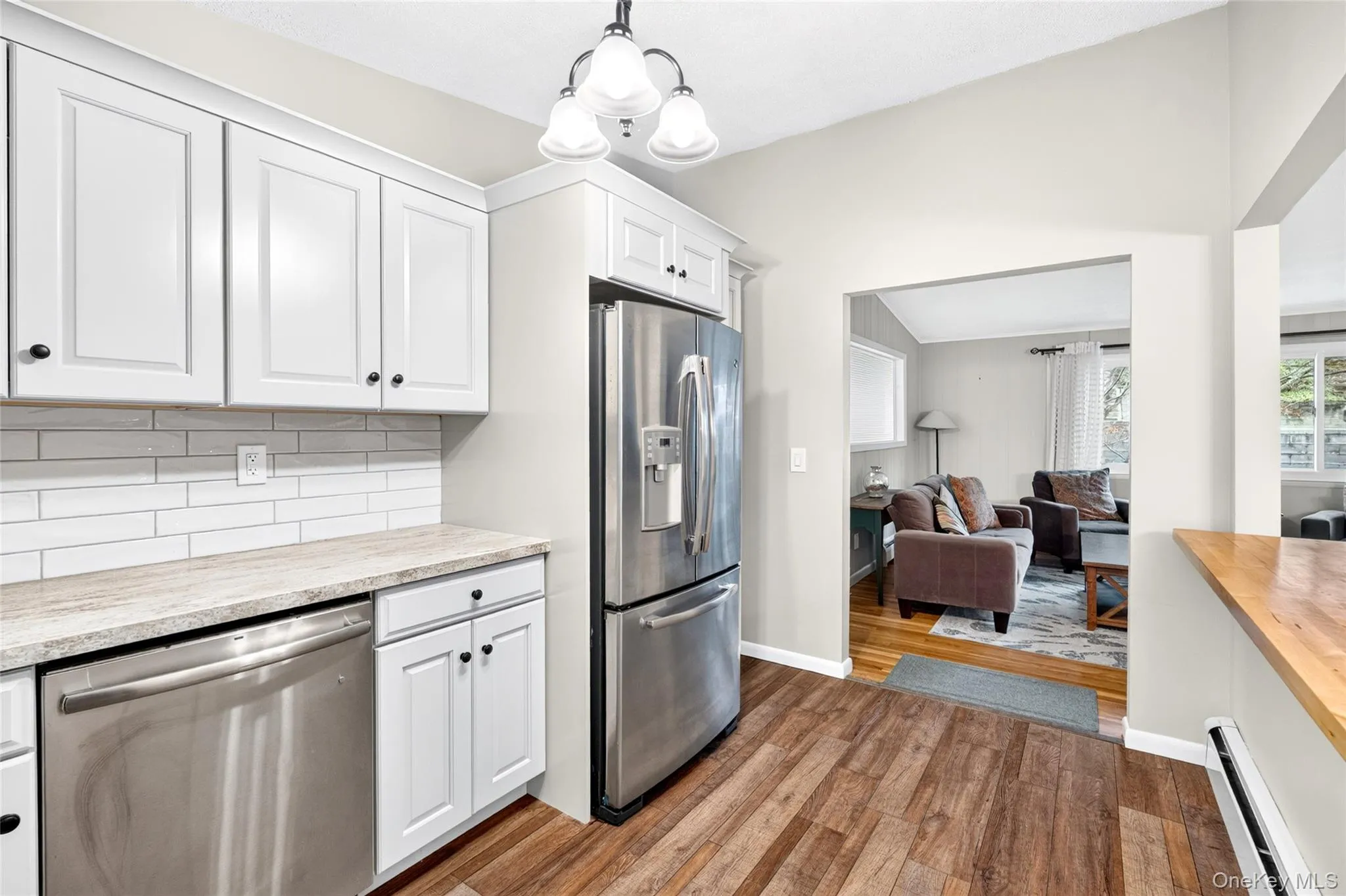 Kitchen featuring white cabinetry, subway tile backsplash, stainless steel appliances, and wood-finish flooring Kitchen featuring white cabinetry, subway tile backsplash, stainless steel appliances, and wood-finish flooring