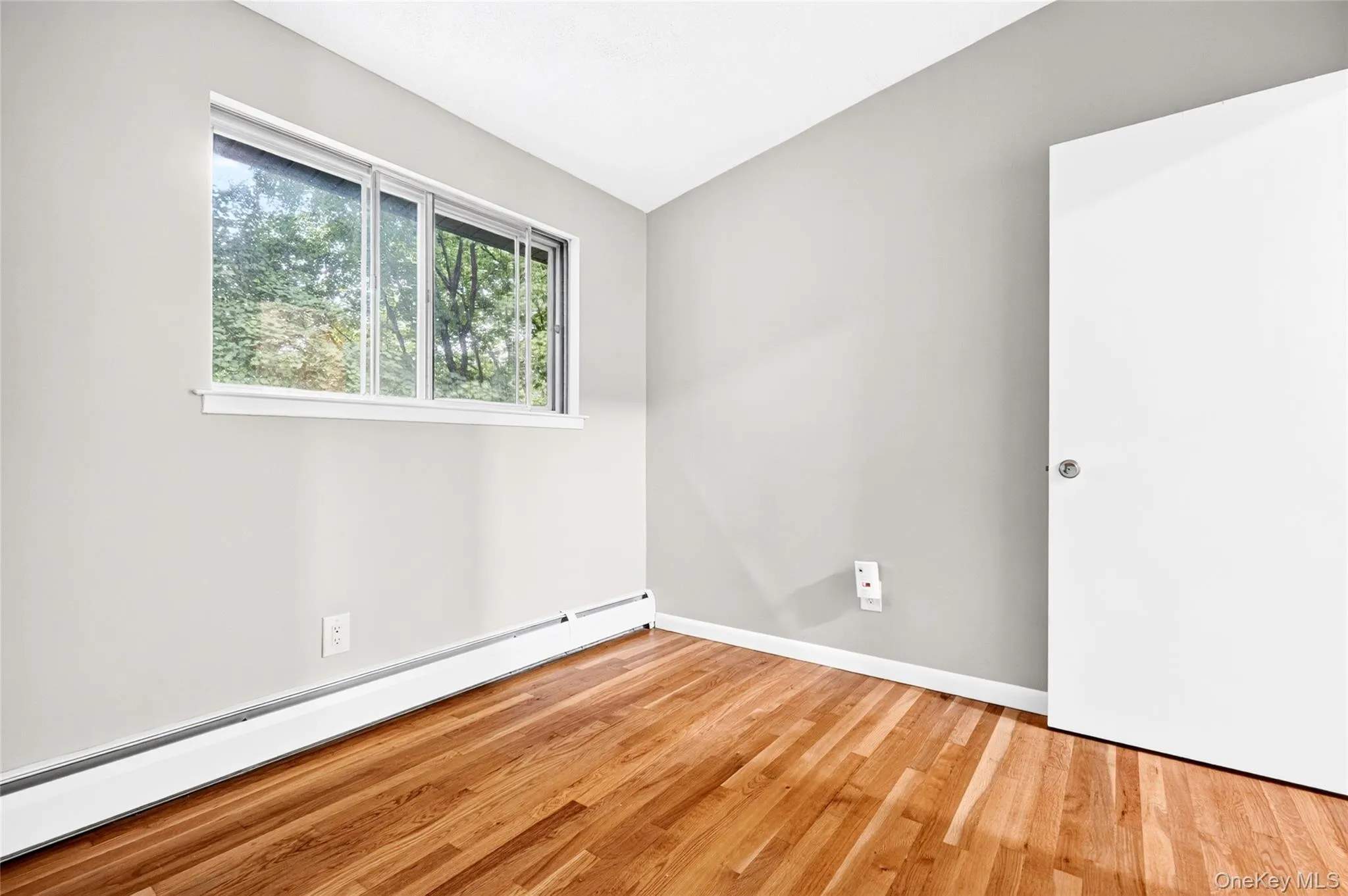 Hardwood flooring, light gray wall finish, white interior door, and white window trim Hardwood flooring, light gray wall finish, white interior door, and white window trim