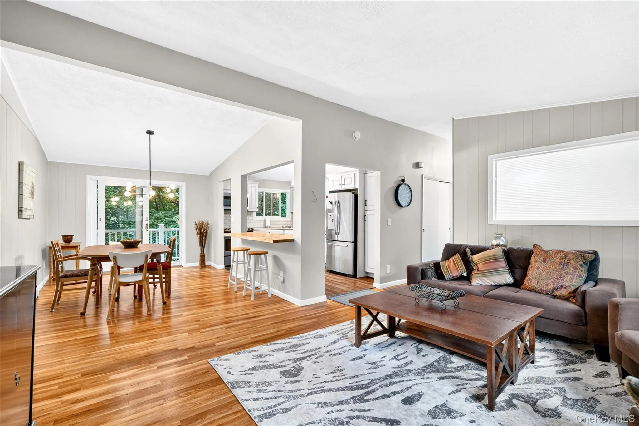 Hardwood flooring extending throughout the dining area, vaulted ceiling, and sliding glass door leading to an outdoor balcony Hardwood flooring extending throughout the dining area, vaulted ceiling, and sliding glass door leading to an outdoor balcony