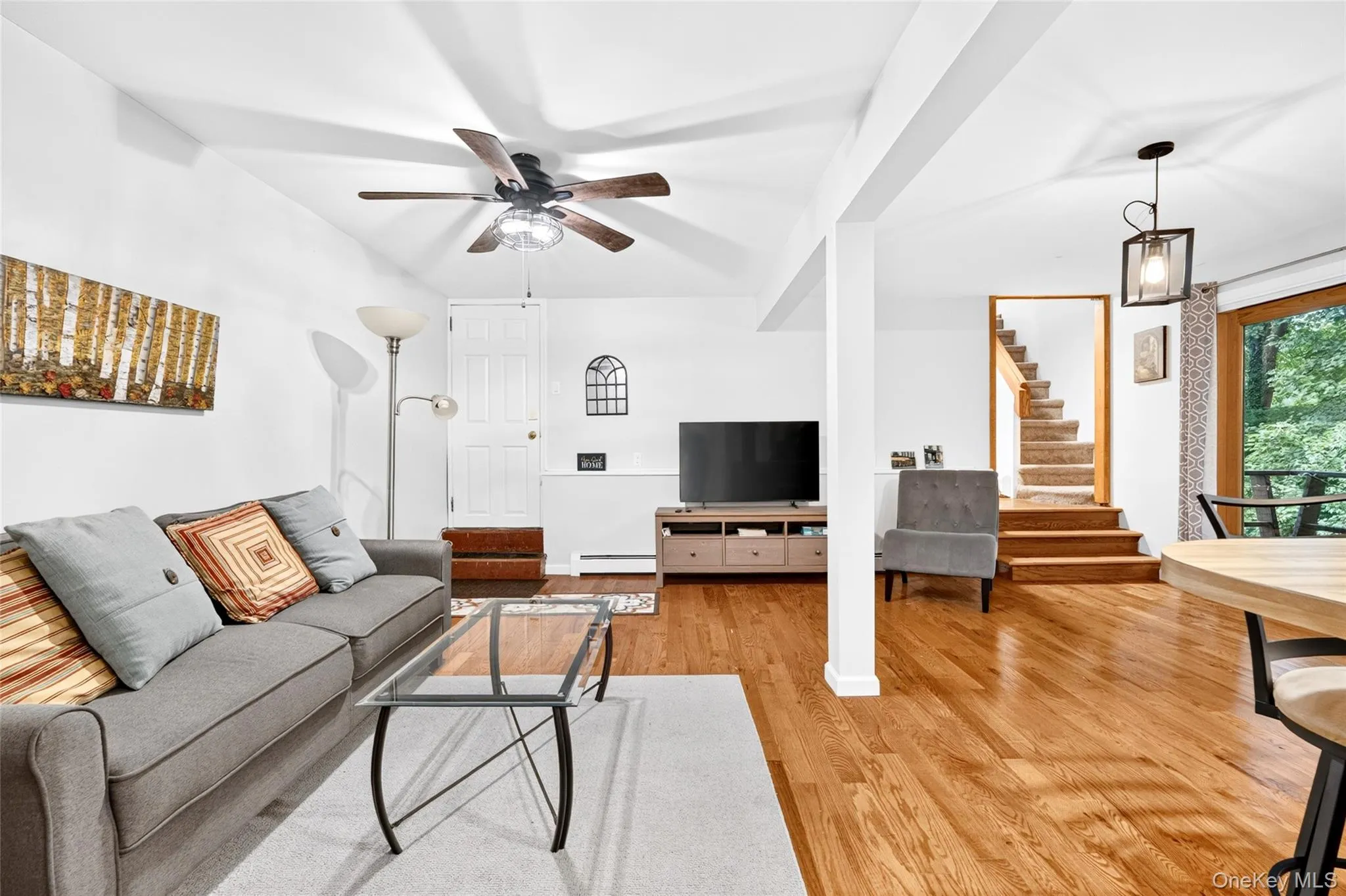 Finished playroom, with a ceiling fan, hardwood flooring, white painted walls, exposed wood stairs, and a pendant light fixture Finished playroom, with a ceiling fan, hardwood flooring, white painted walls, exposed wood stairs, and a pendant light fixture