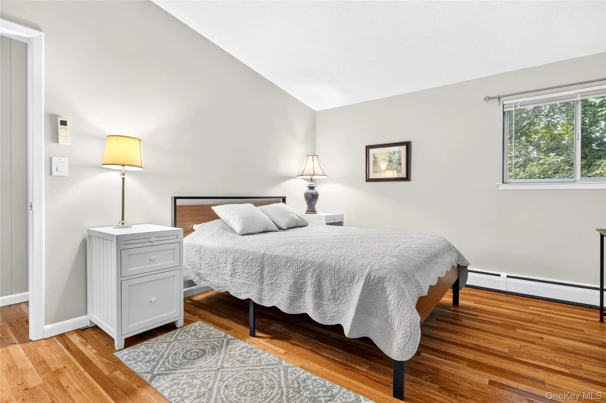 Wood-finish flooring, neutral wall tones, and a window with exterior foliage Wood-finish flooring, neutral wall tones, and a window with exterior foliage