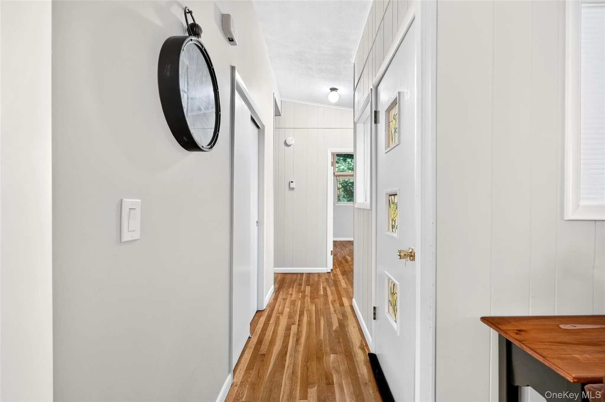Wood-finish flooring throughout, bright white walls, white paneled door with decorative inserts, and white window blinds Wood-finish flooring throughout, bright white walls, white paneled door with decorative inserts, and white window blinds