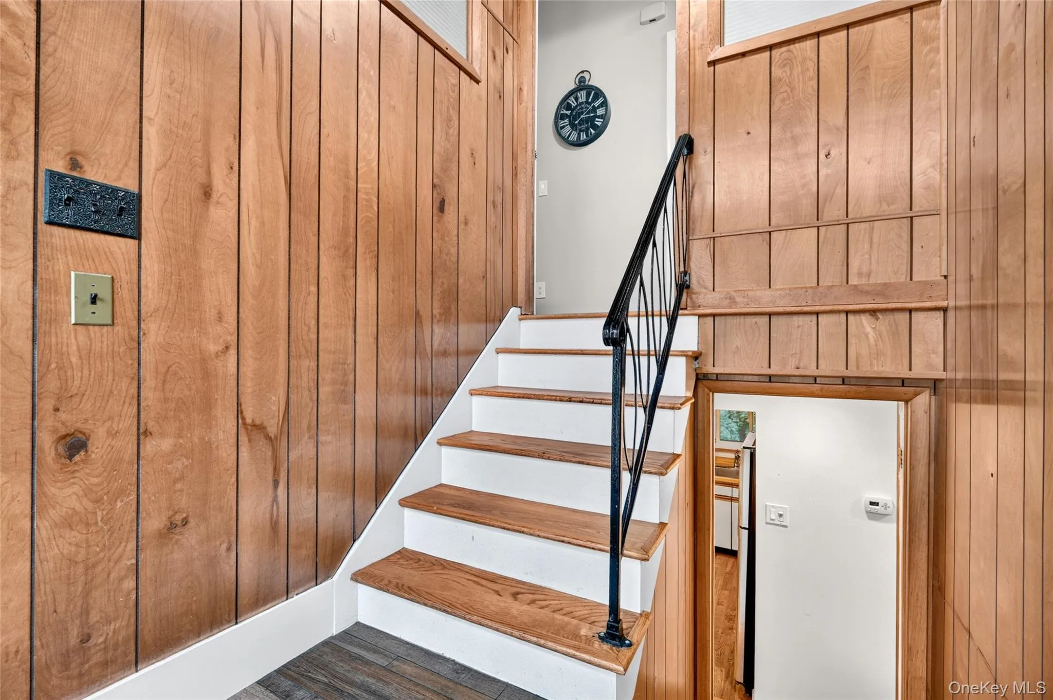 Wood-paneled walls featuring a staircase with wood treads and white risers Wood-paneled walls featuring a staircase with wood treads and white risers