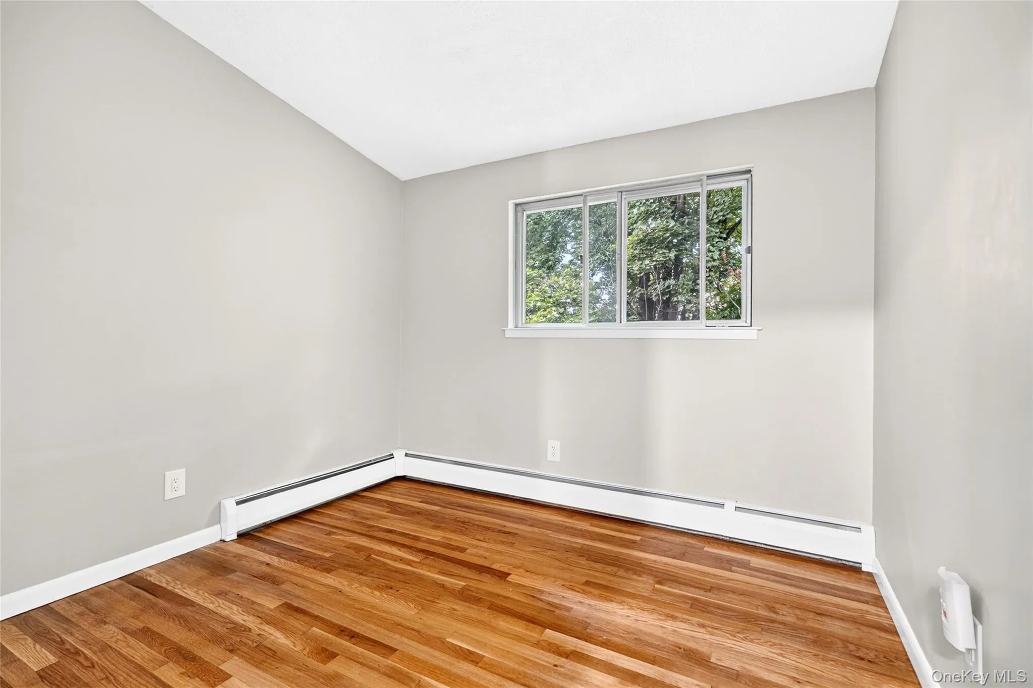 Natural wood flooring, light gray wall finishes, sliding window, and white trim Natural wood flooring, light gray wall finishes, sliding window, and white trim