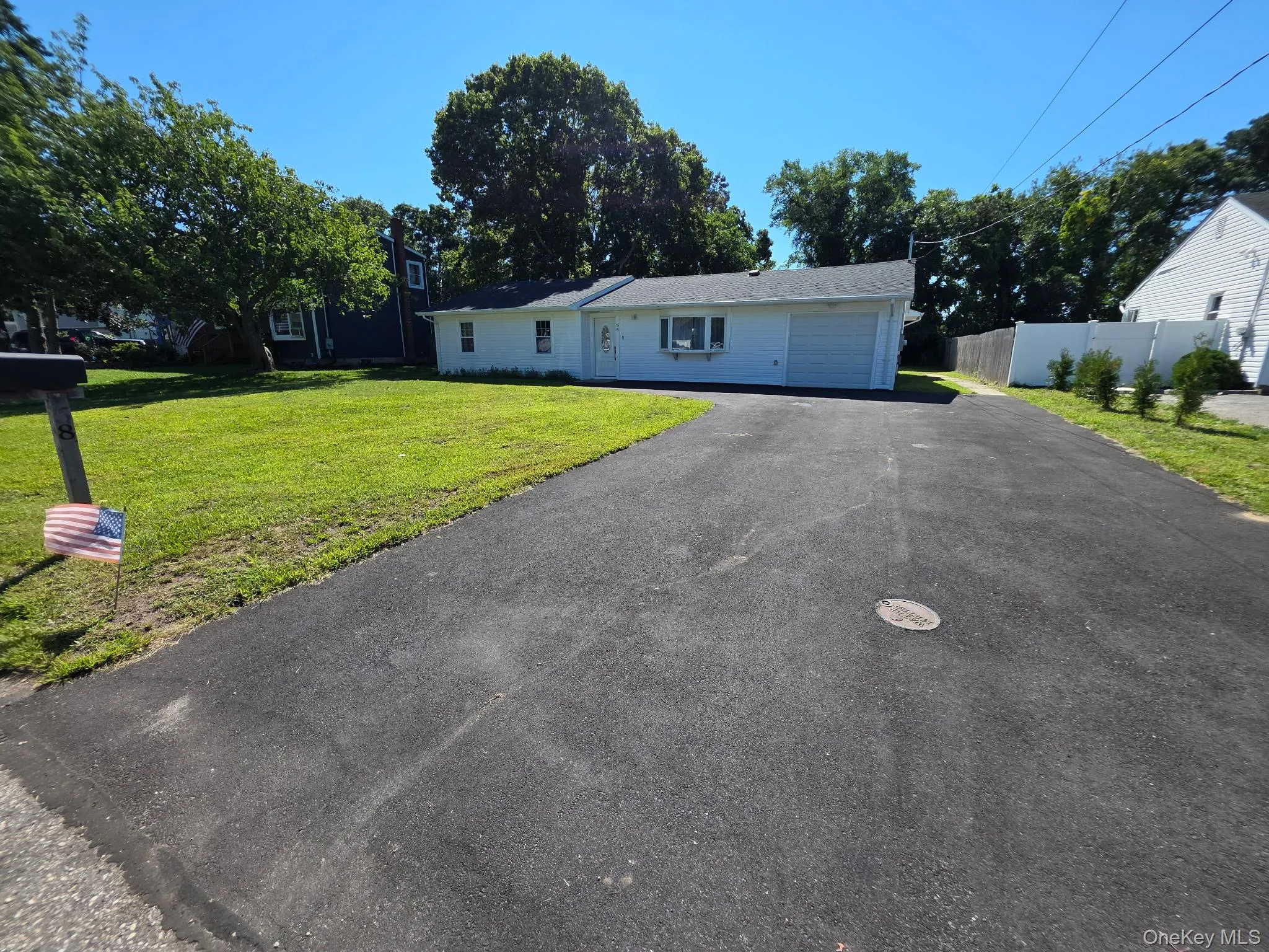 Single-story residence with a white exterior, attached garage, and a paved driveway Single-story residence with a white exterior, attached garage, and a paved driveway