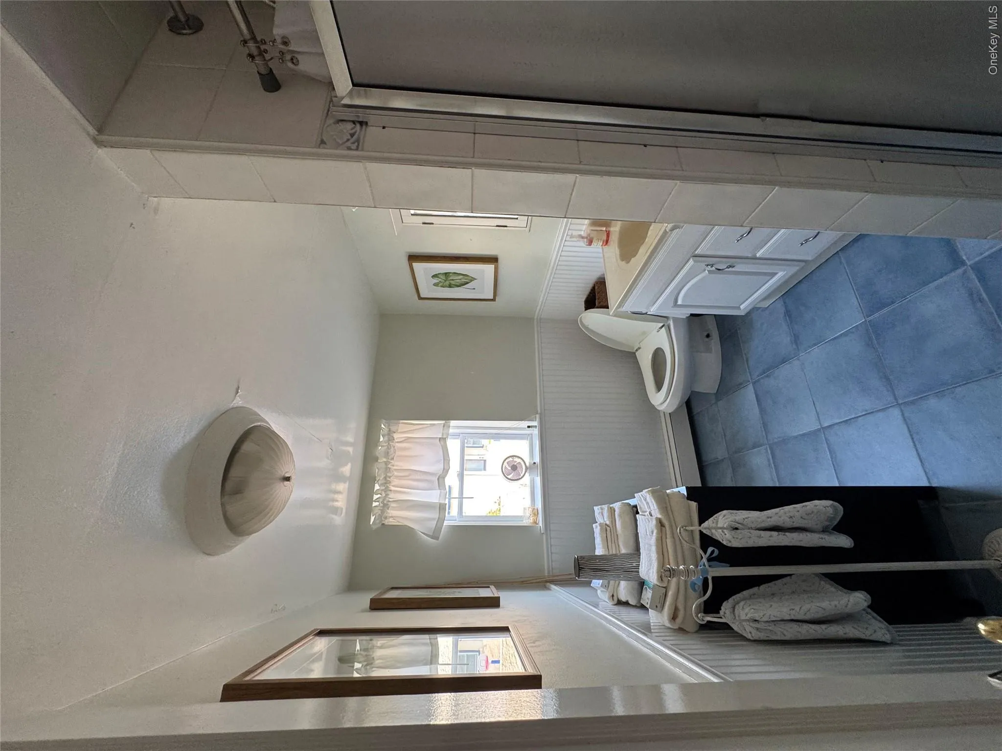 Full bathroom featuring wainscoting, a stall shower, vanity, a baseboard heating unit, and tile patterned floors Full bathroom featuring wainscoting, a stall shower, vanity, a baseboard heating unit, and tile patterned floors