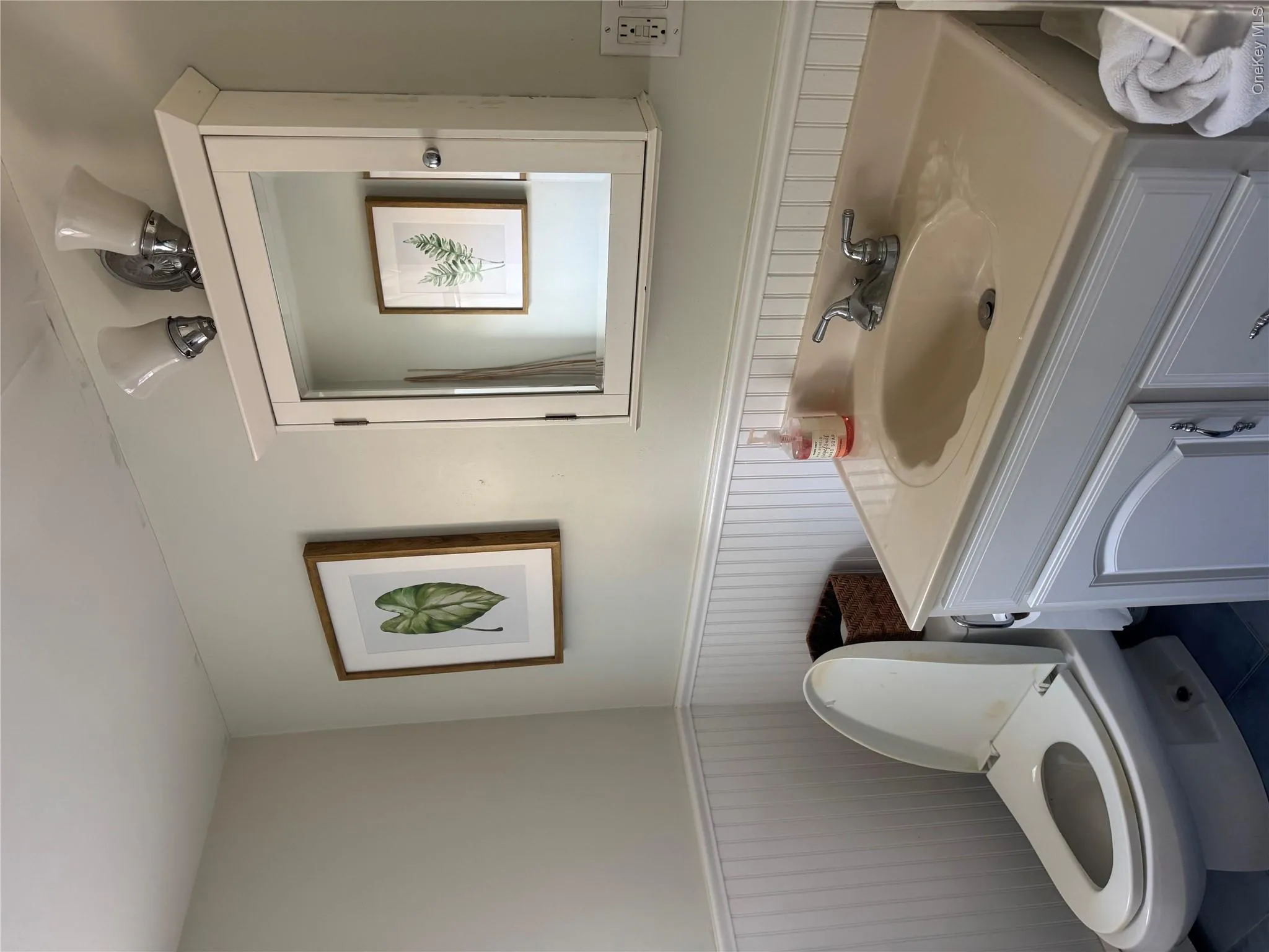 Half bathroom featuring vanity, a wainscoted wall, and dark tile patterned floors Half bathroom featuring vanity, a wainscoted wall, and dark tile patterned floors