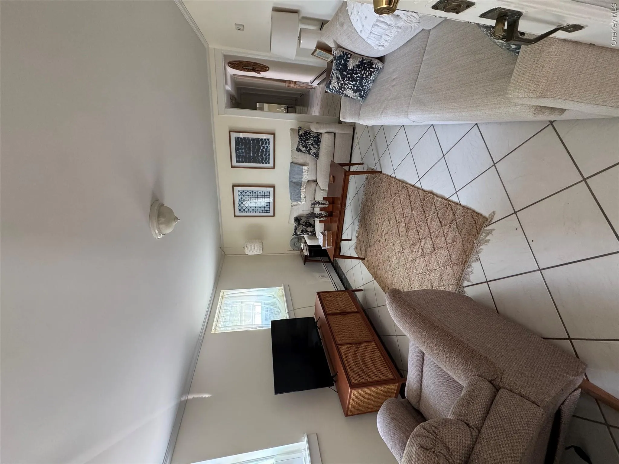 Living room featuring light tile patterned flooring, crown molding, and a baseboard radiator Living room featuring light tile patterned flooring, crown molding, and a baseboard radiator