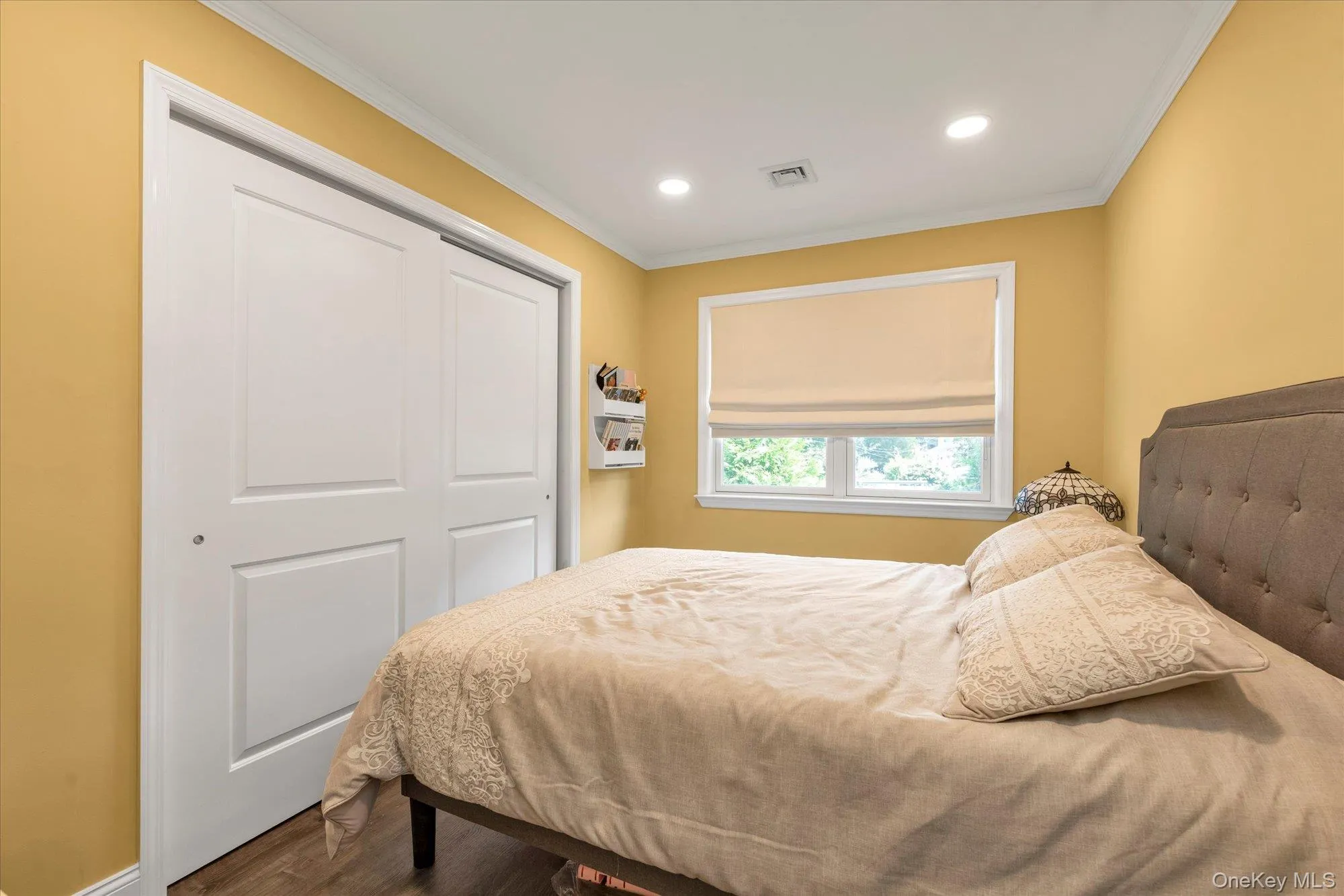 Bedroom #2 Recessed ceiling lighting, crown molding, white trim, sliding panel closet doors, and wood-finish flooring Bedroom #2 Recessed ceiling lighting, crown molding, white trim, sliding panel closet doors, and wood-finish flooring