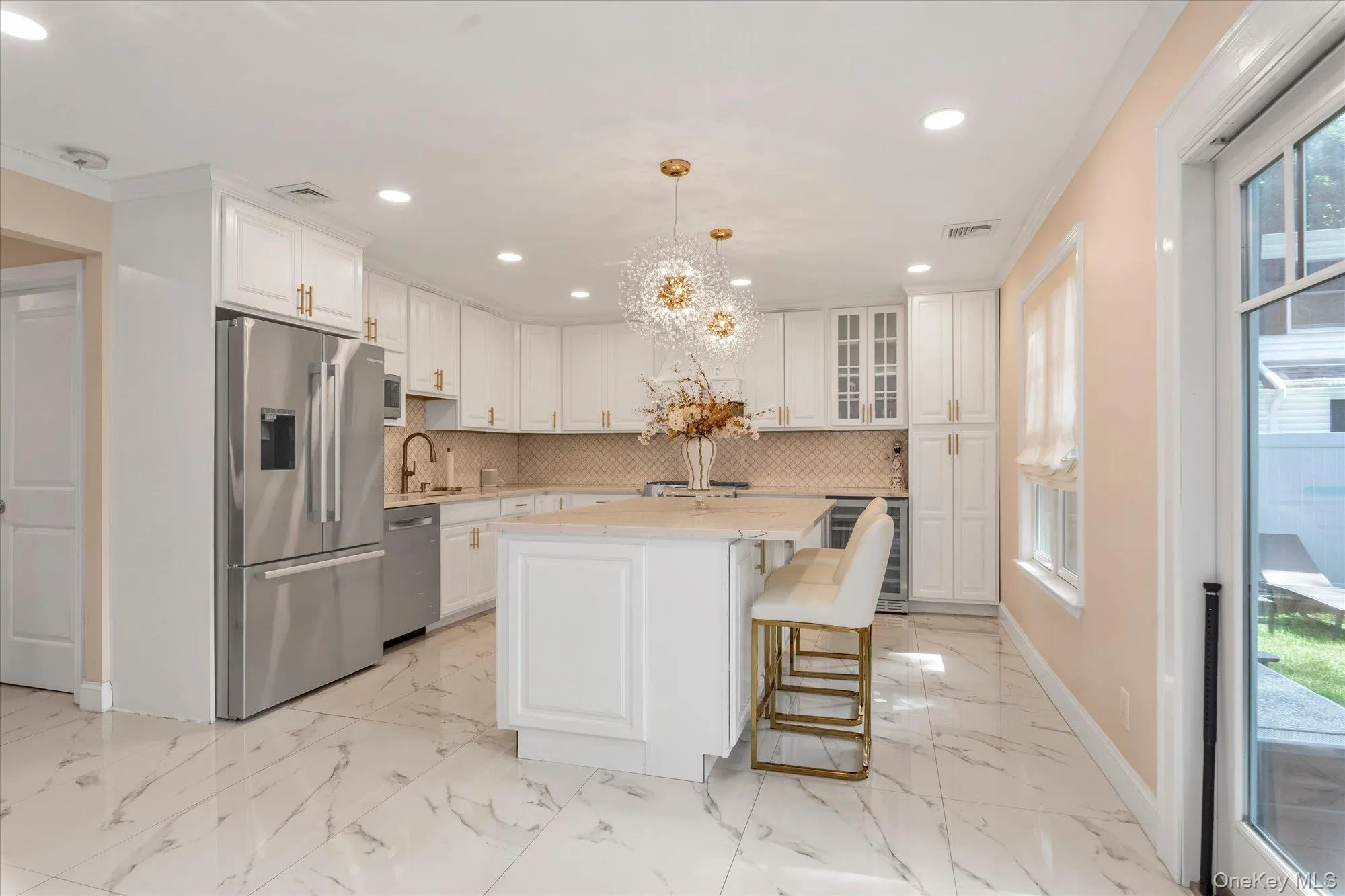Cooks kitchen featuring white cabinetry, 2023 refrigerator, Bosch Dishwasher, Center island, Quartz Counters, Stainless steel appliances, beverage refrigerator + 2023 sideXside refrigerator, oversized porcelain tile flooring, and decorative pendant lighting. 2023 replaced washer and dryer which is conveniently located off kitchen. Cooks kitchen featuring white cabinetry, 2023 refrigerator, Bosch Dishwasher, Center island, Quartz Counters, Stainless steel appliances, beverage refrigerator + 2023 sideXside refrigerator, oversized porcelain tile flooring, and decorative pendant lighting. 2023 replaced washer and dryer which is conveniently located off kitchen.
