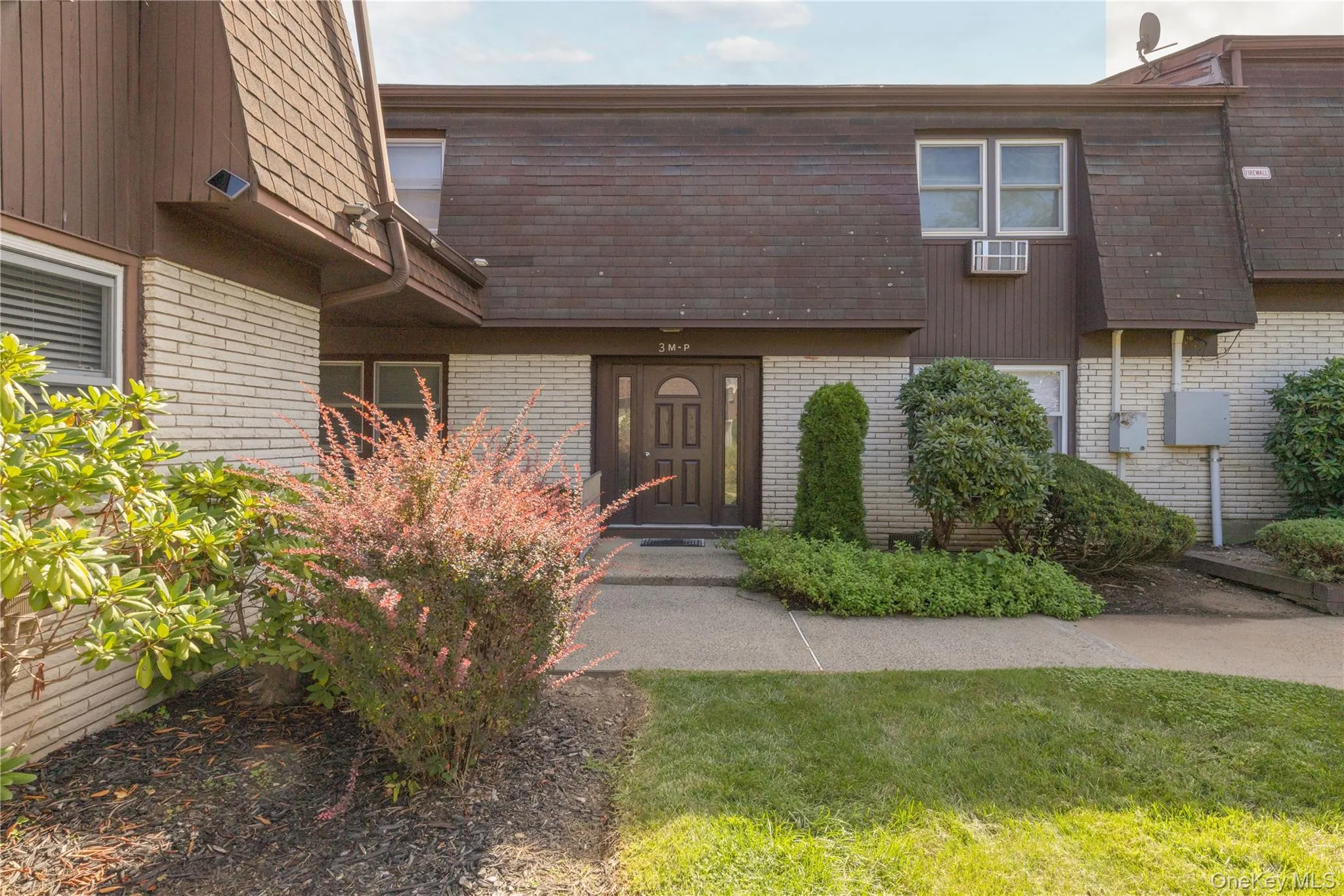 Front exterior featuring a brown shingle roof, light-colored brick siding, and a dark-toned entry door Front exterior featuring a brown shingle roof, light-colored brick siding, and a dark-toned entry door