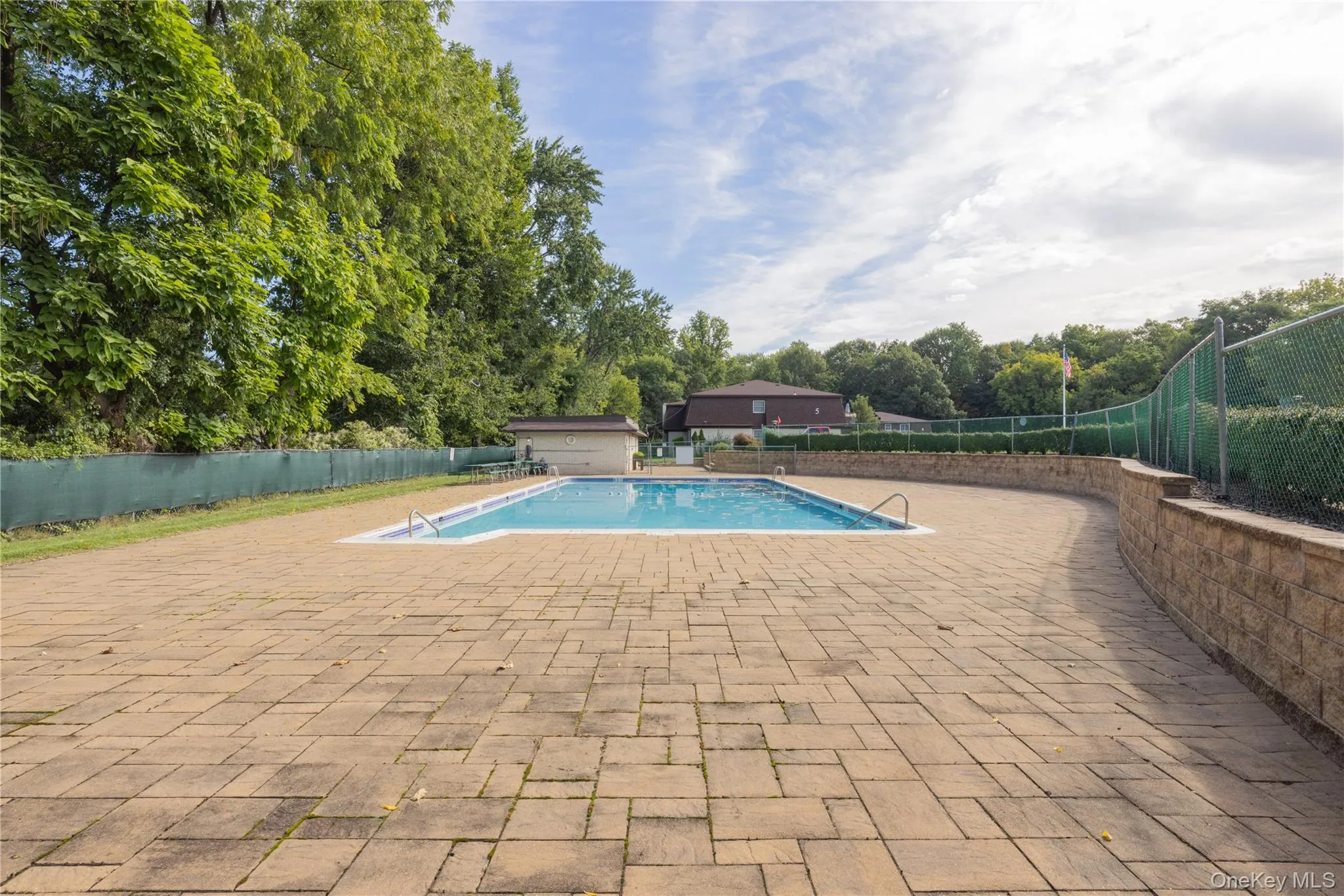 Swimming pool with integrated steps, surrounded by a paver patio and stone retaining wall Swimming pool with integrated steps, surrounded by a paver patio and stone retaining wall