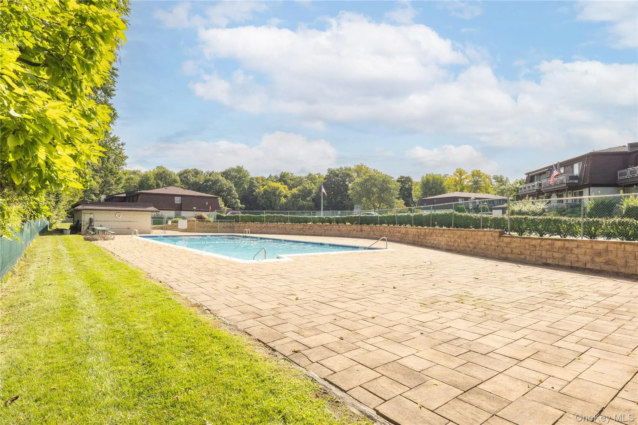 Outdoor swimming pool with integrated steps, surrounded by a paver patio and a low retaining wall Outdoor swimming pool with integrated steps, surrounded by a paver patio and a low retaining wall