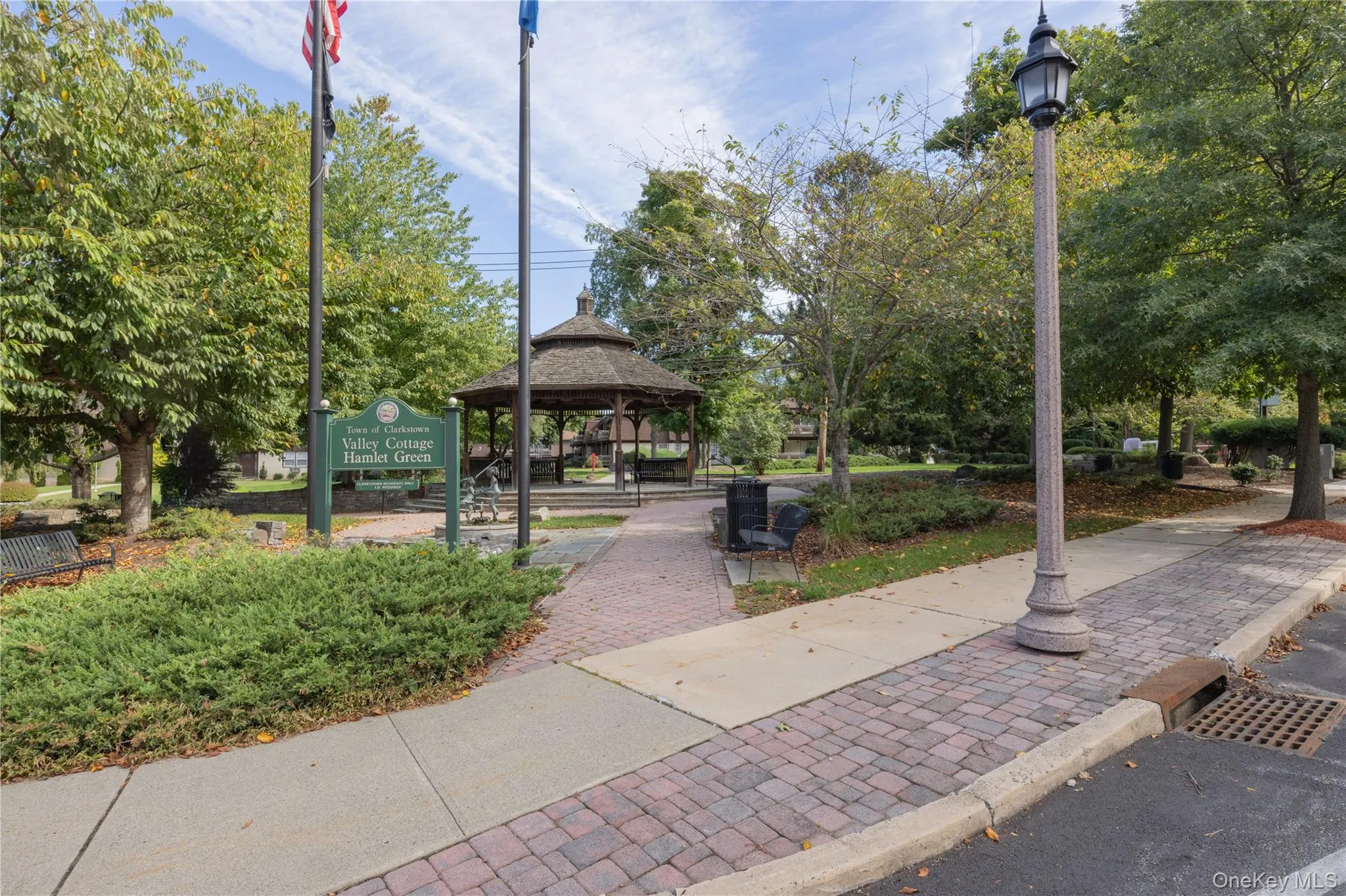 Park setting featuring a gazebo, mature trees, paved walkways, and a decorative street lamp Park setting featuring a gazebo, mature trees, paved walkways, and a decorative street lamp