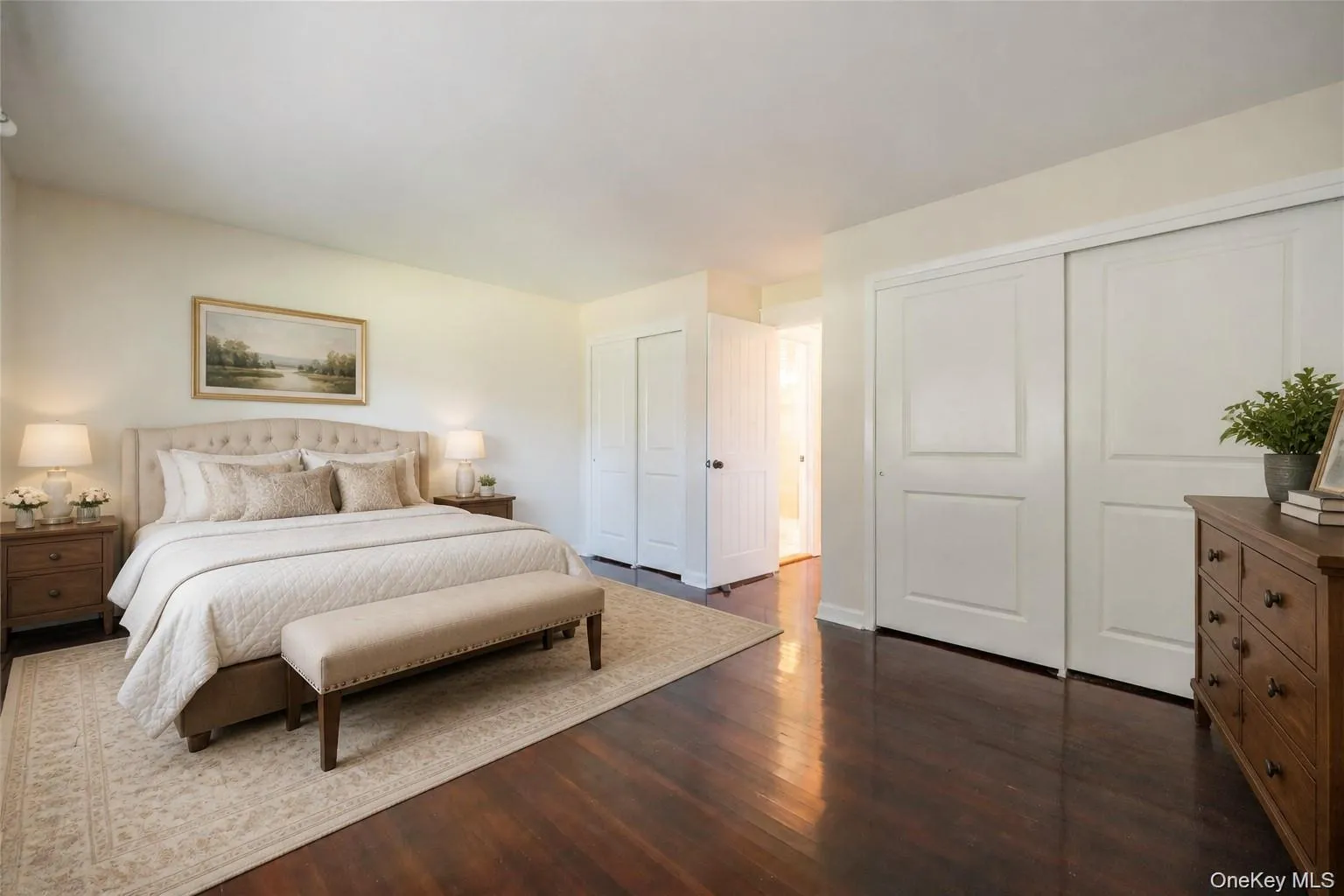 Rich wood-finish flooring, two large sliding closet doors, and a neutral color palette. Staged photo Rich wood-finish flooring, two large sliding closet doors, and a neutral color palette. Staged photo